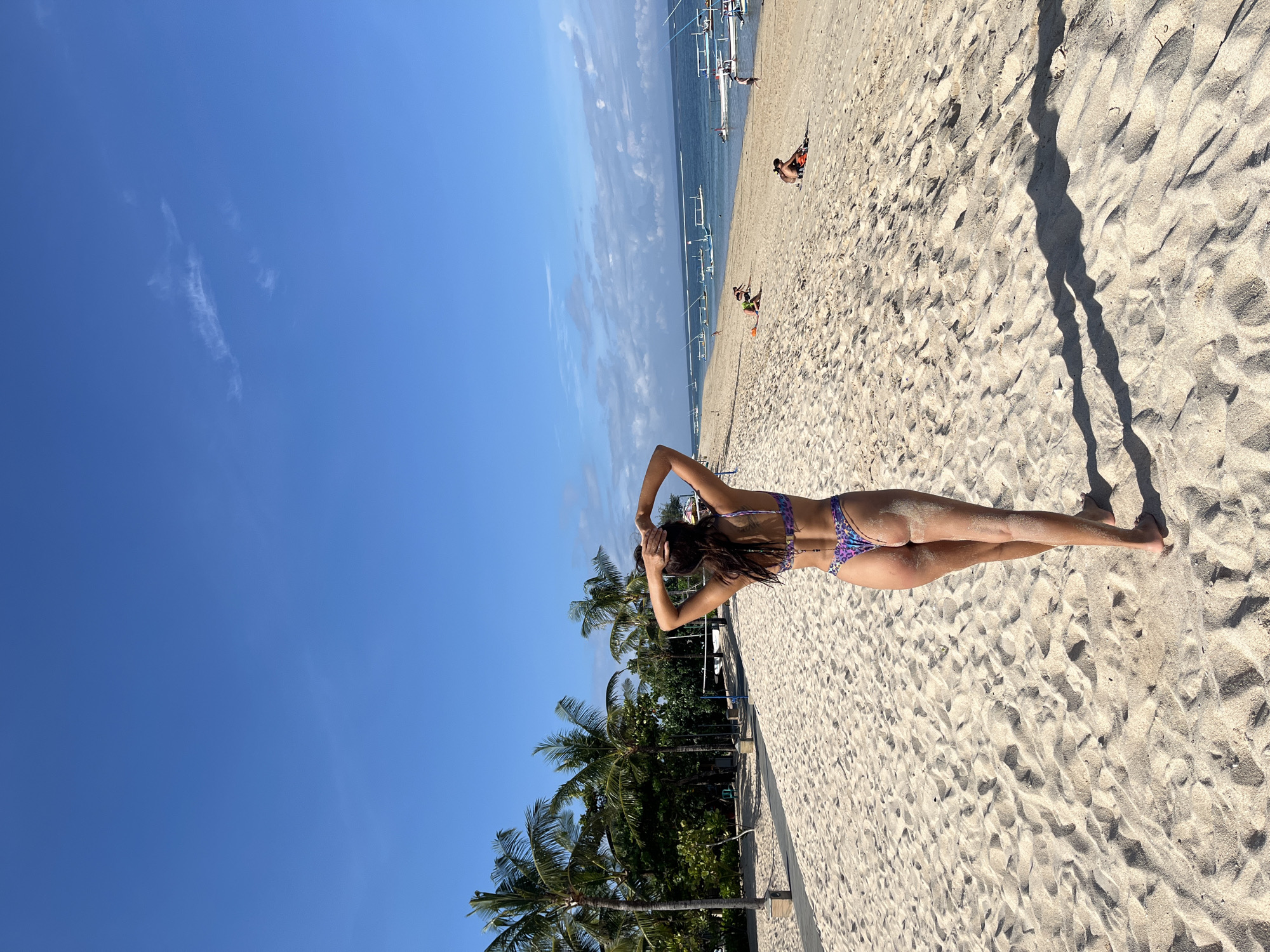 Woman sunbathes on Kuta Selatan beach under sunny skies