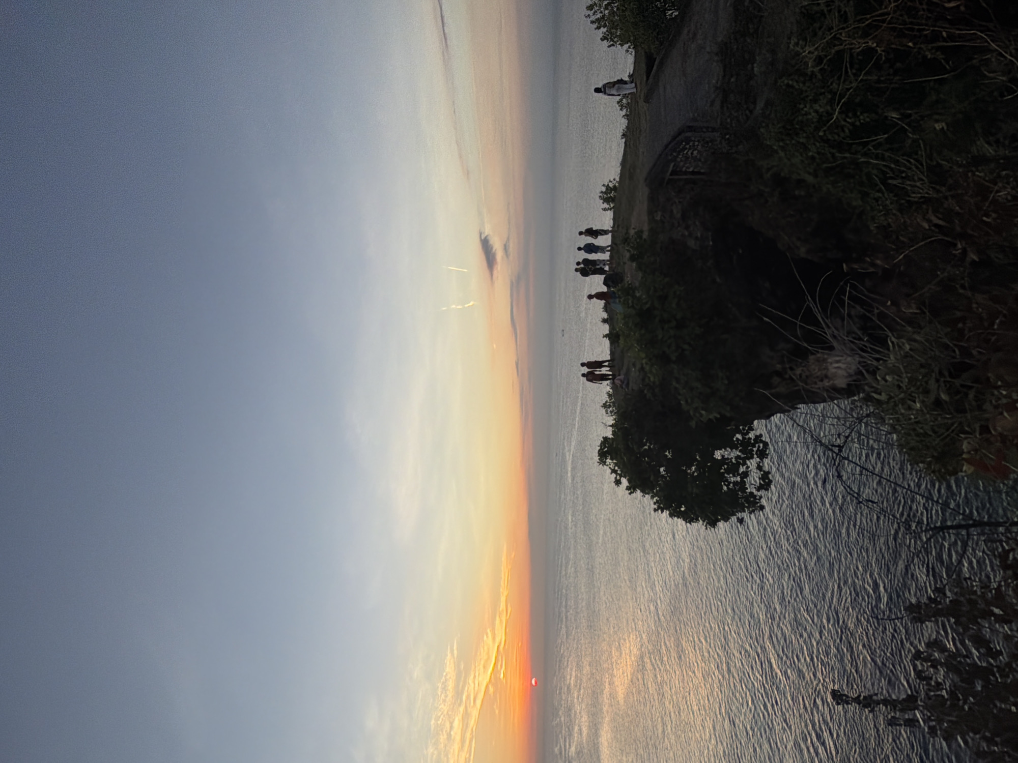 Cliff-side sunset watch over a calm tropical ocean