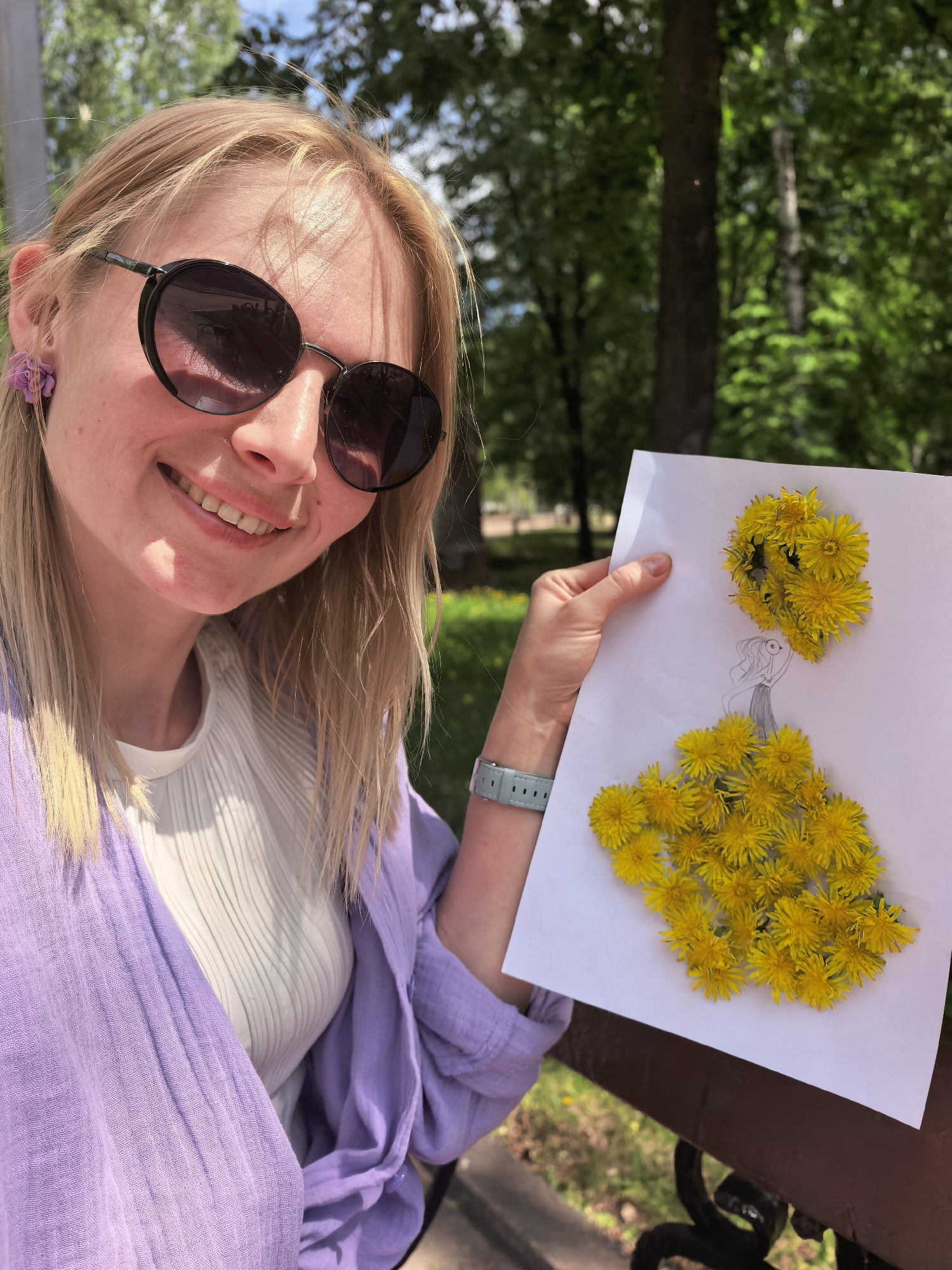 Woman creates dandelion art during park outing with baby