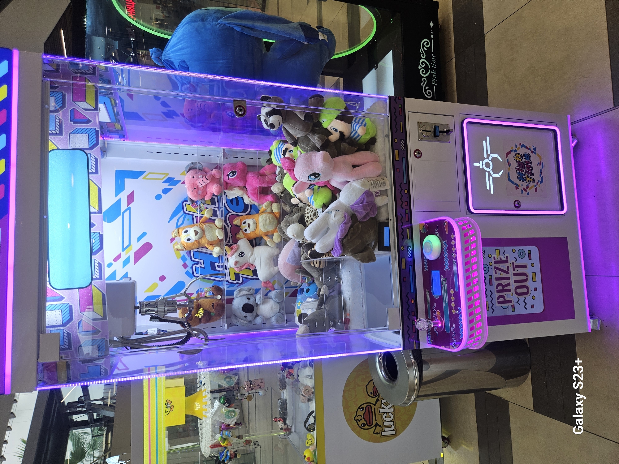 Neon-lit claw machine full of plush toys in Bulgarian mall