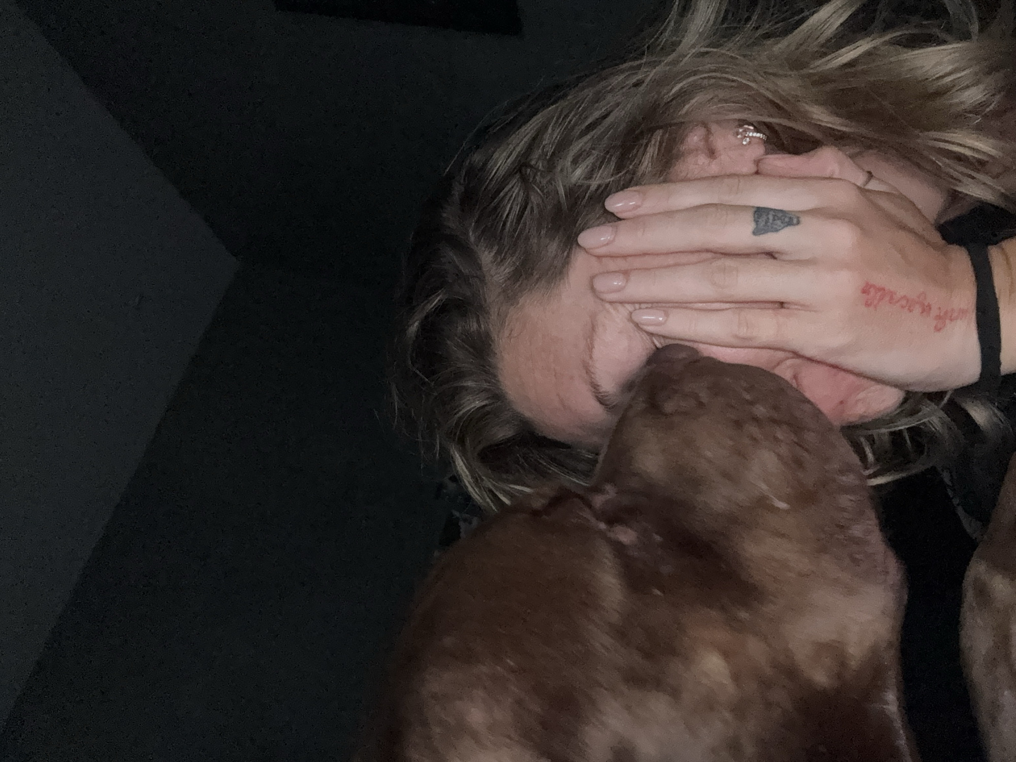 Person with tattooed hands rests with dog in Mengwi