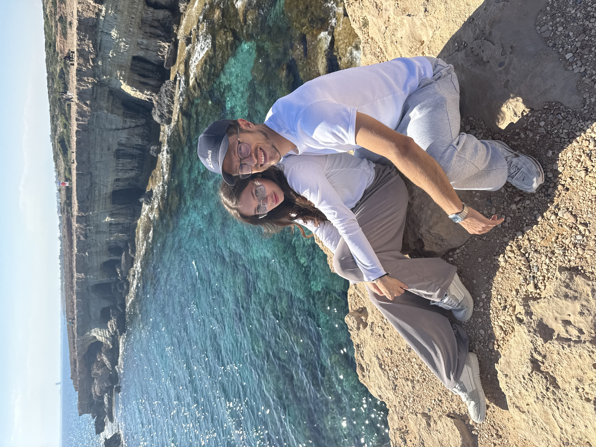 Couple relaxes on rocky cliff overlooking sea in Cyprus