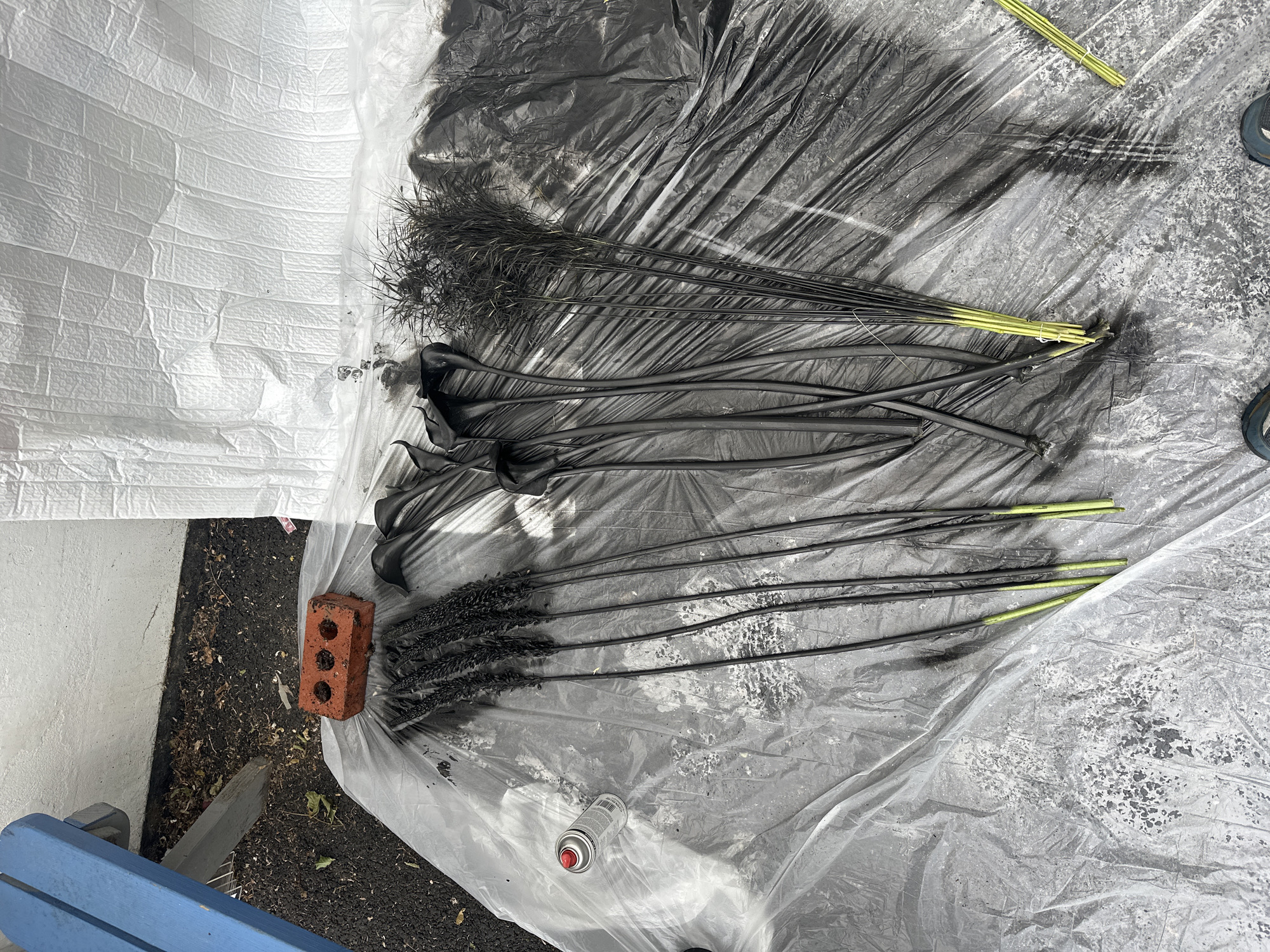 Artist spray-paints artificial flowers black in London outdoor workspace