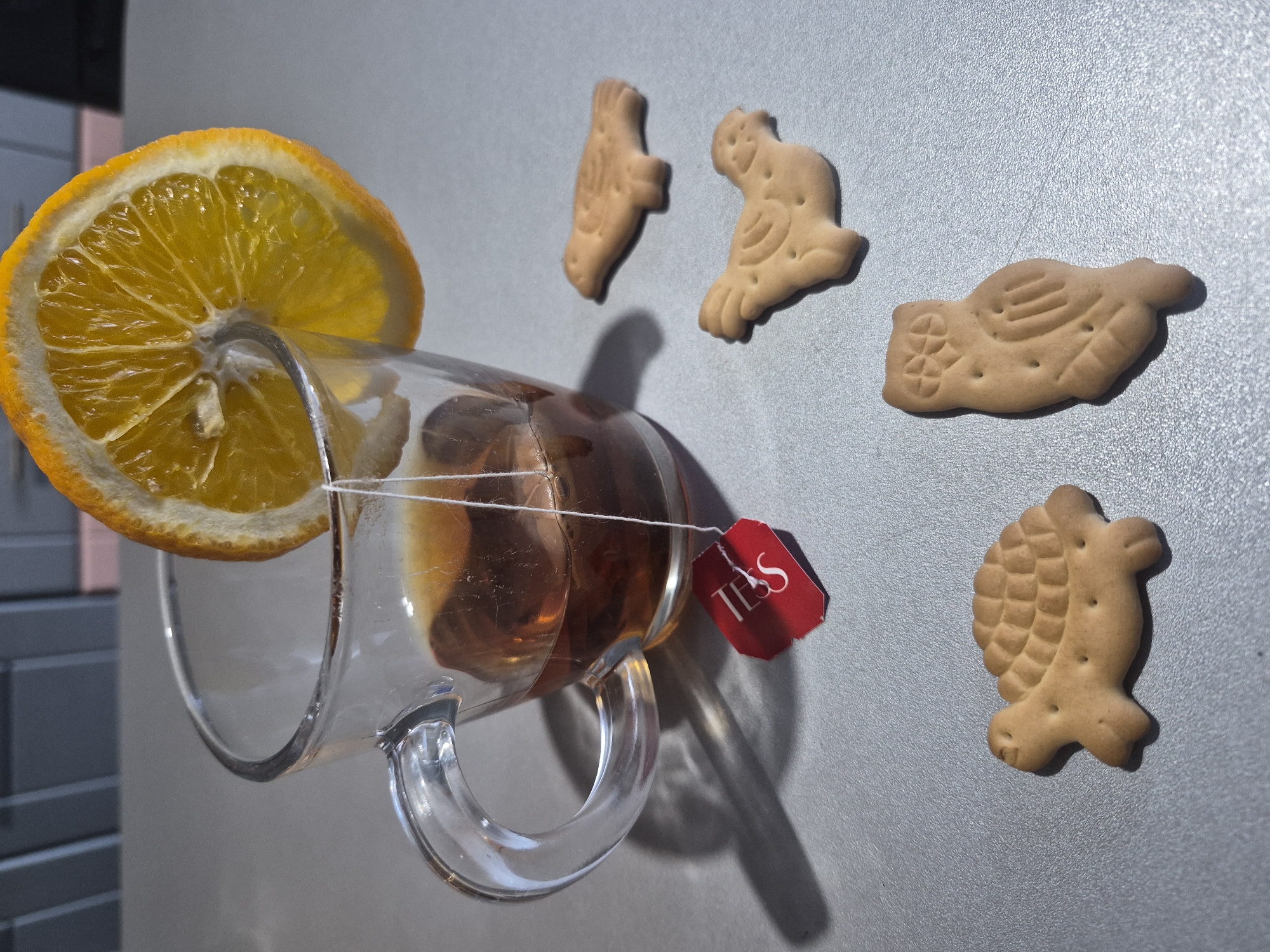 Person enjoys tea with orange slice and biscuits