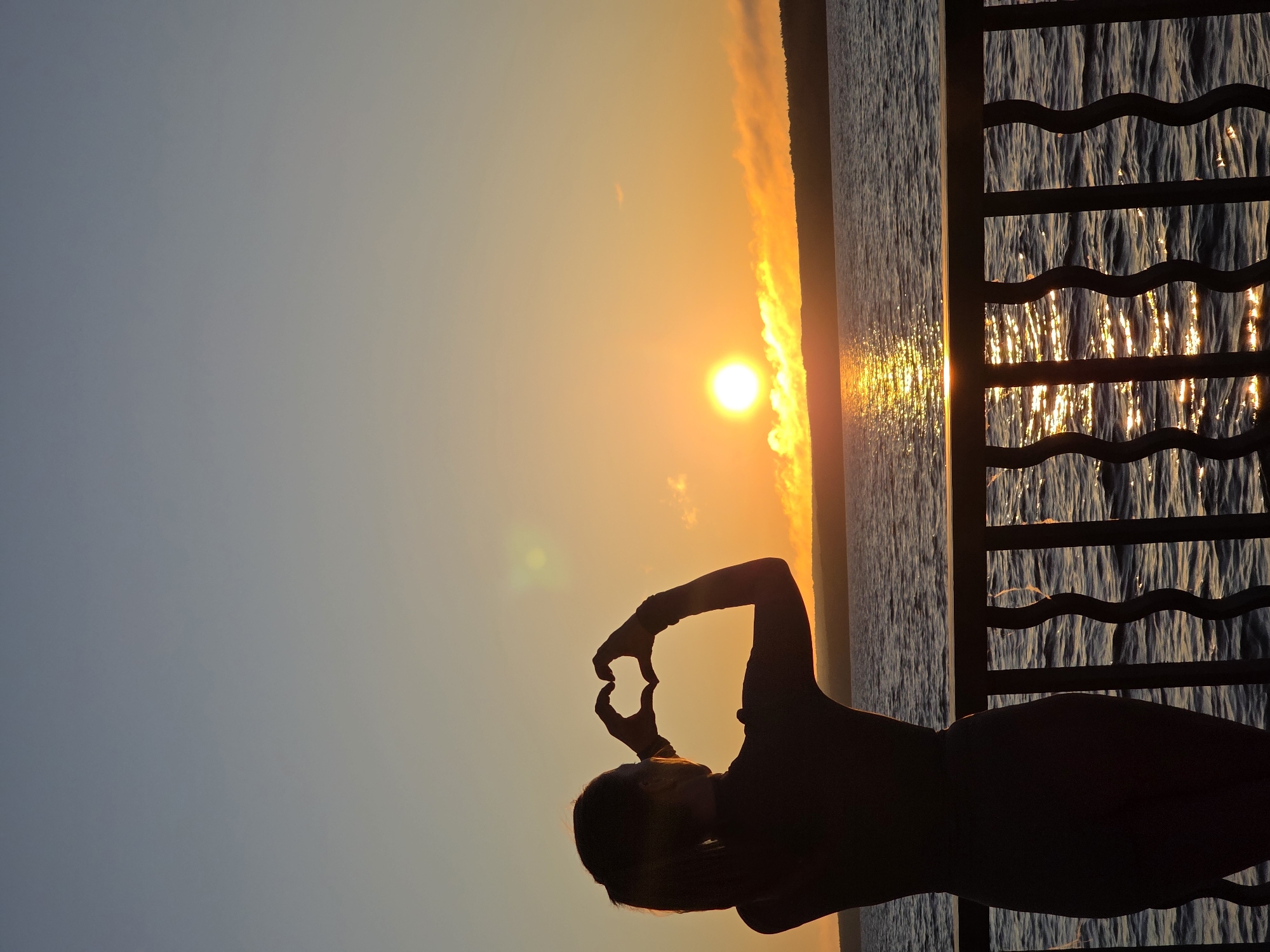 Person makes heart gesture on balcony during Chaikovsky sunset
