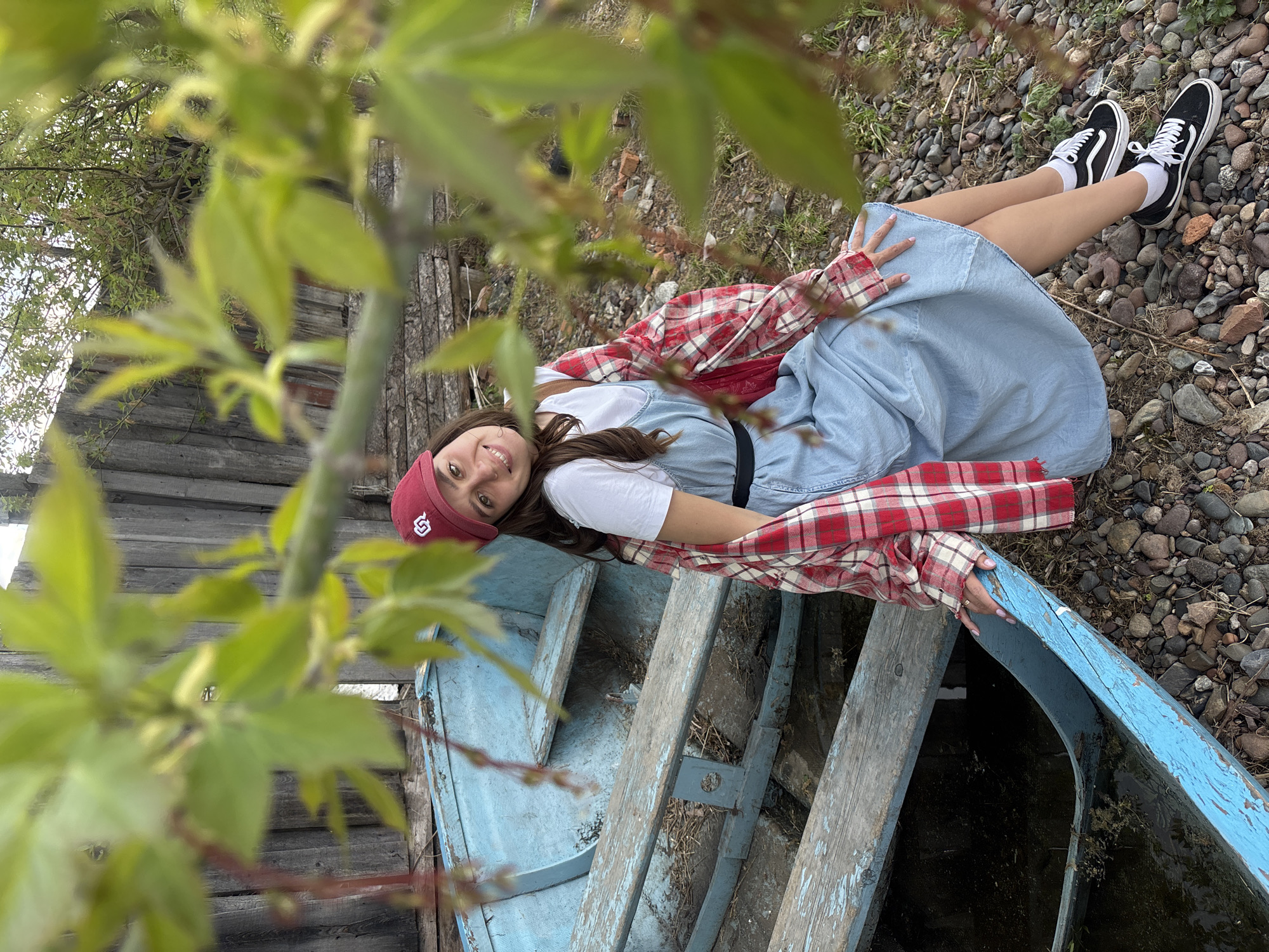 Woman relaxes in boat by rural Russian waterfront