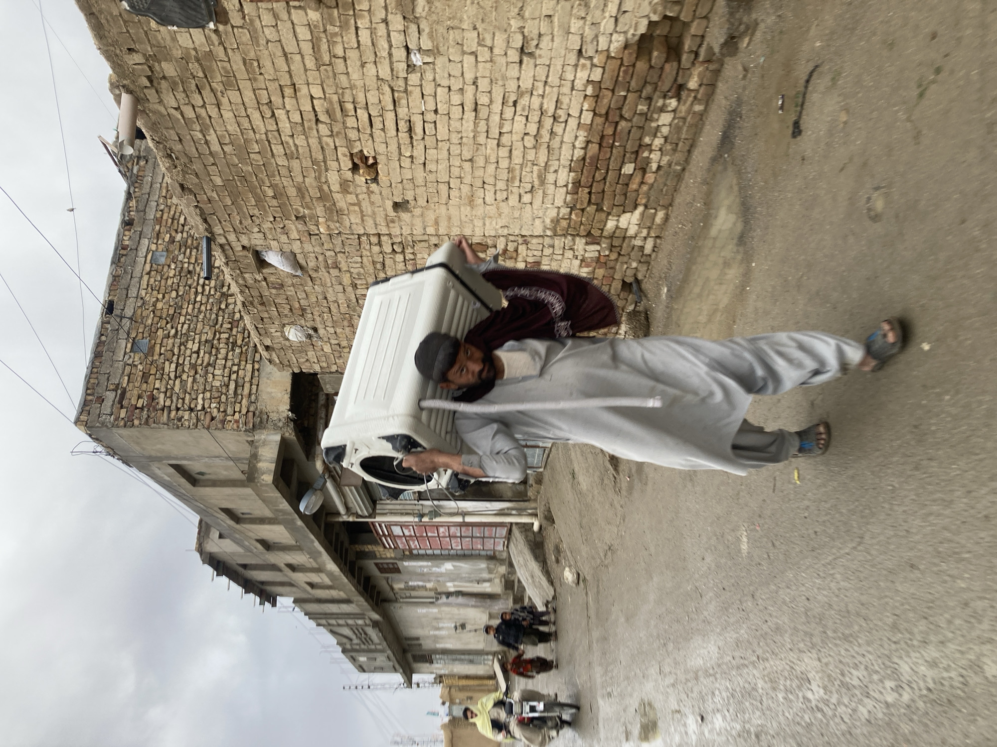 Men transport washing machine through narrow Quetta alley
