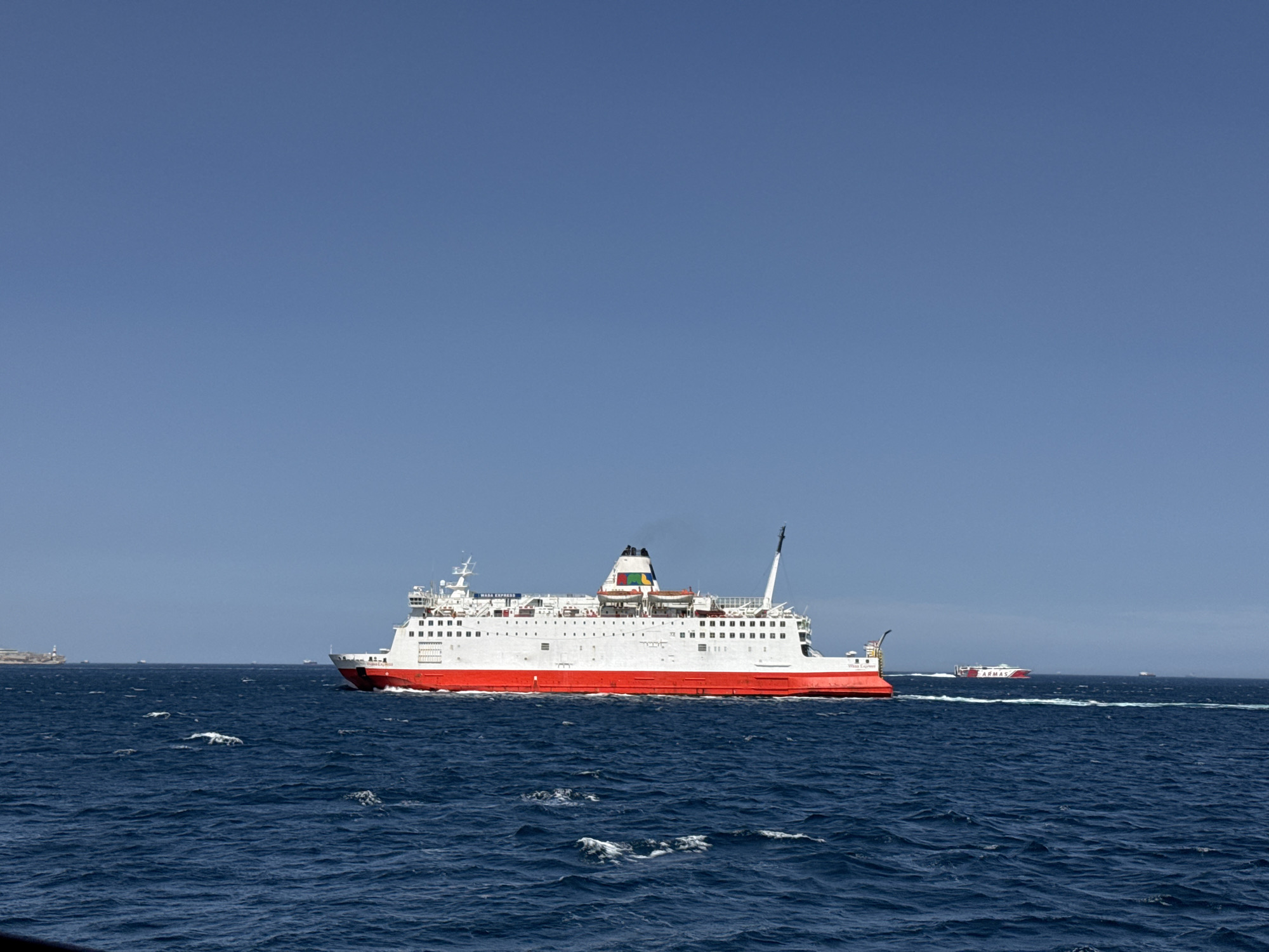 Red and white ferry crossing calm blue waters off Spain