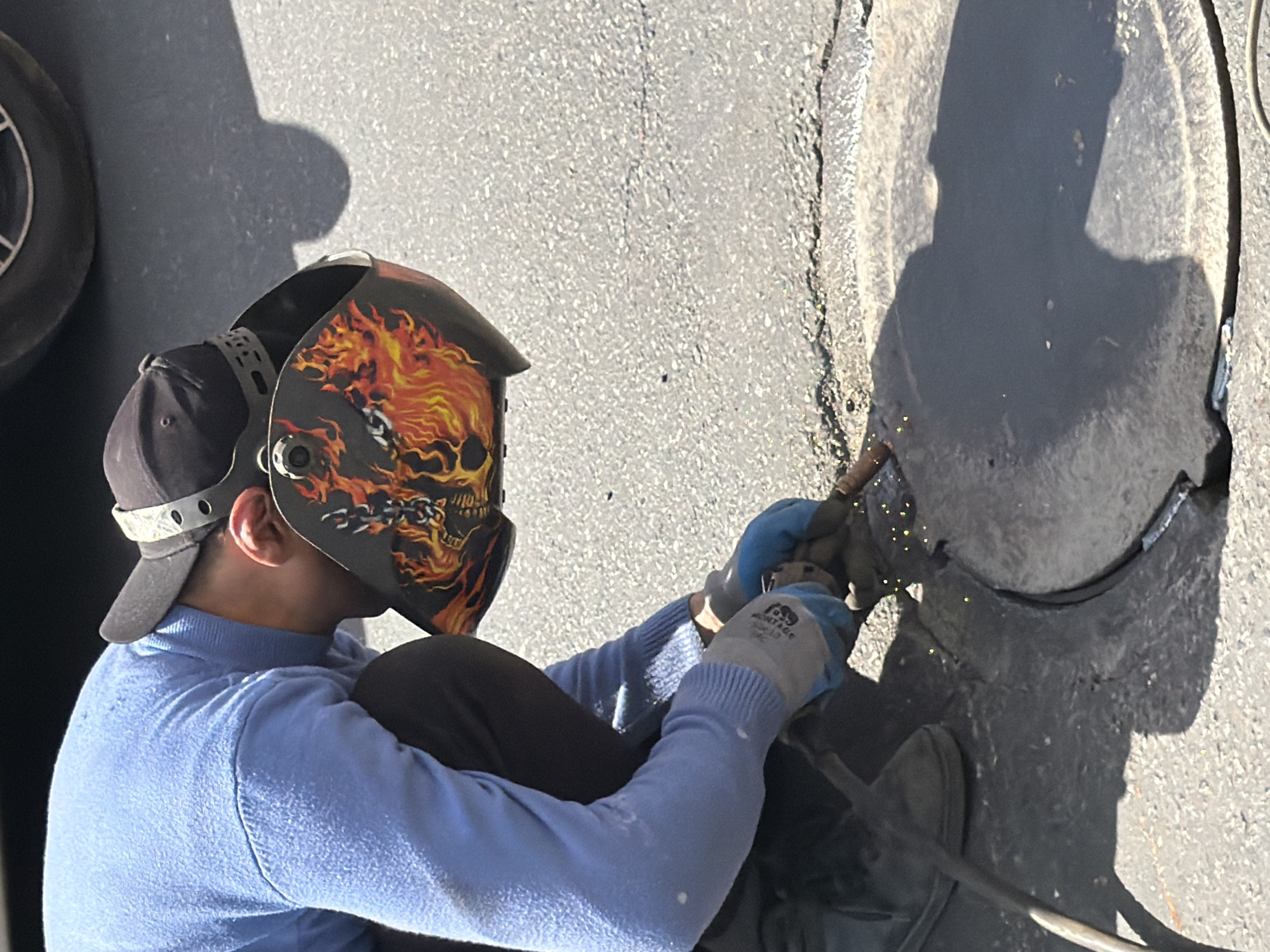 Workers conduct outdoor metalwork on rusted plate in Yerevan