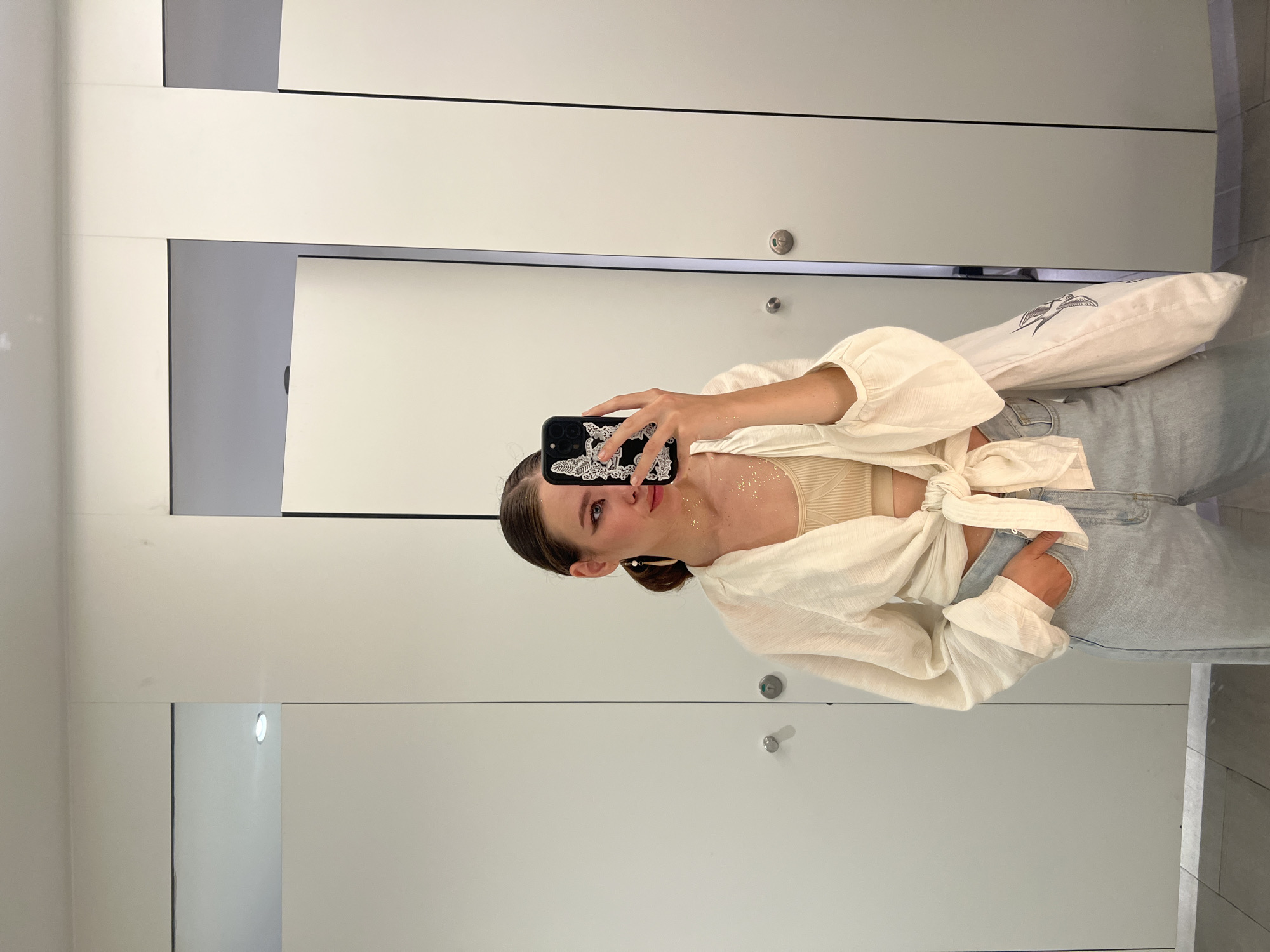 Woman in gold dress takes bathroom selfie while eating