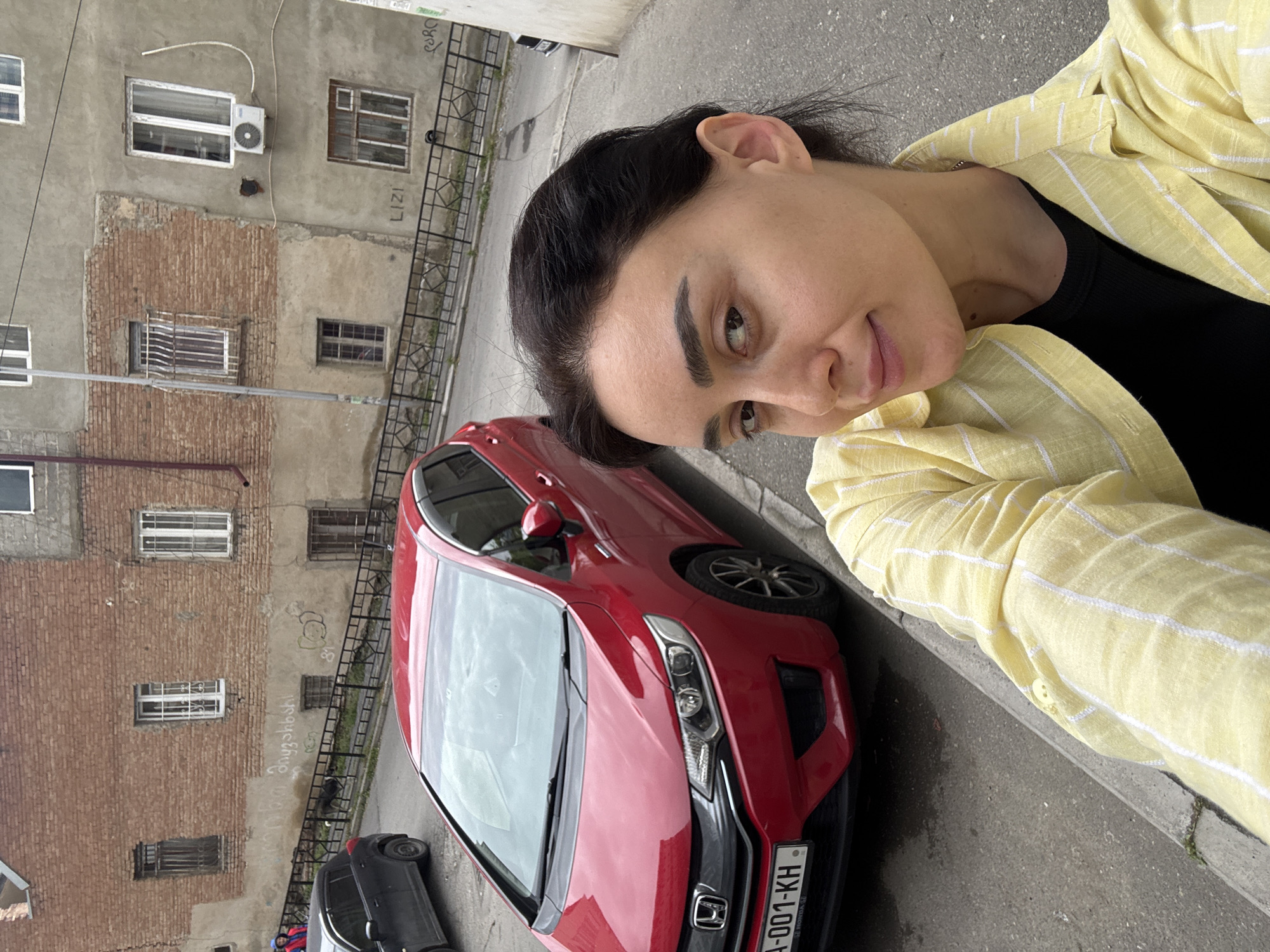 Woman takes selfie in overcast Tbilisi street scene