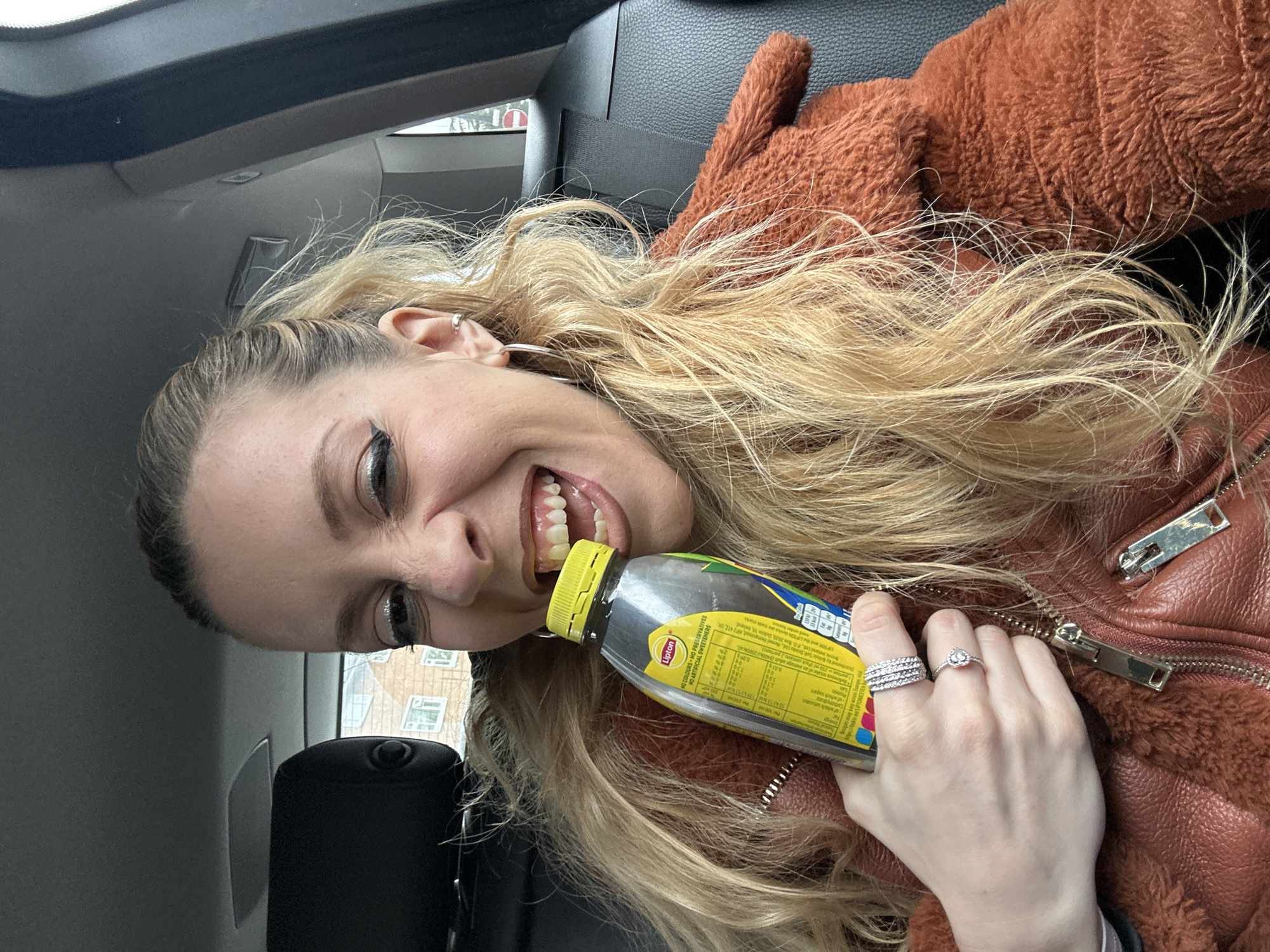 Woman enjoys iced tea in car in London