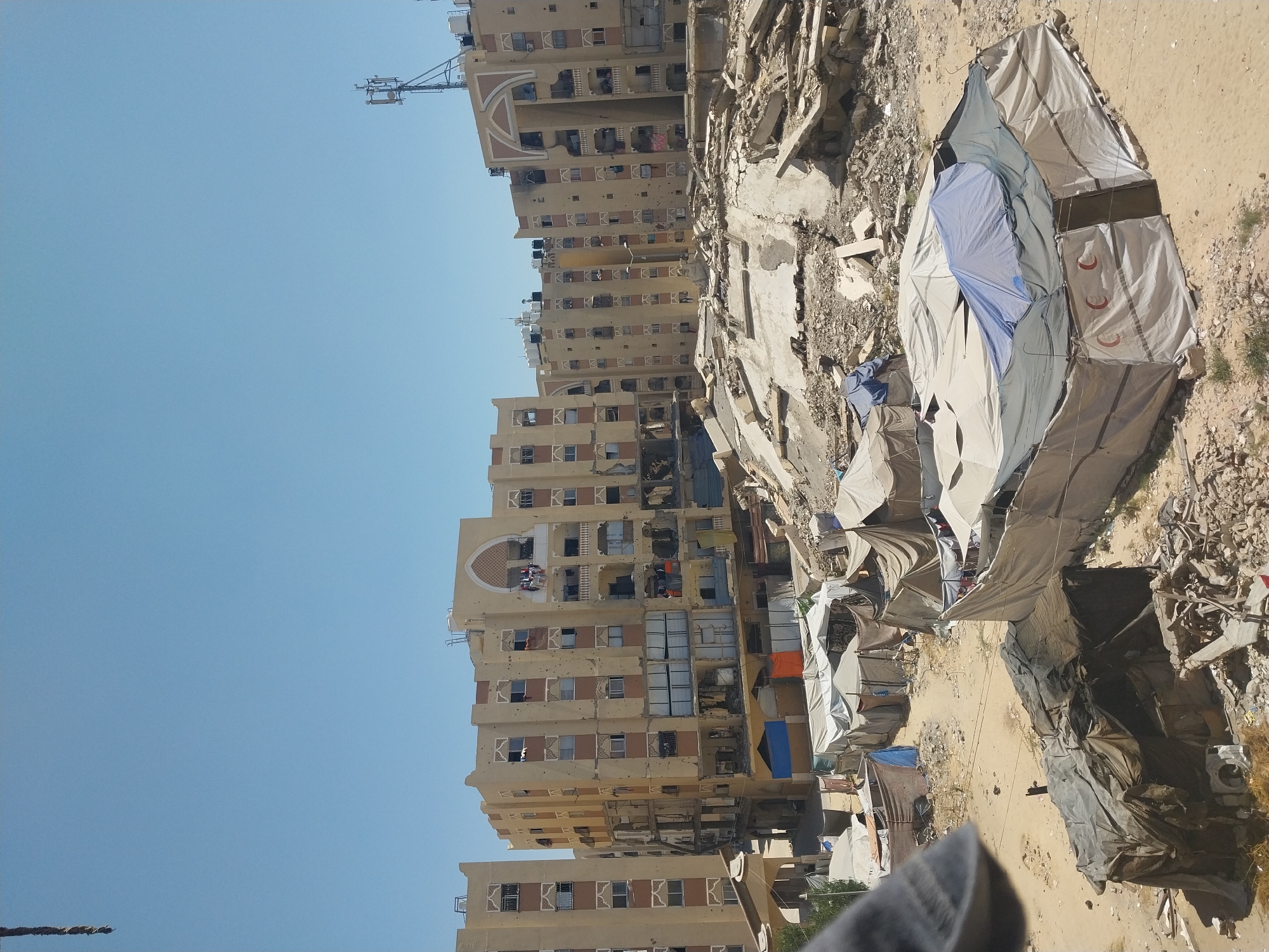 Destroyed apartment buildings alongside displacement tents in Khan Yunis