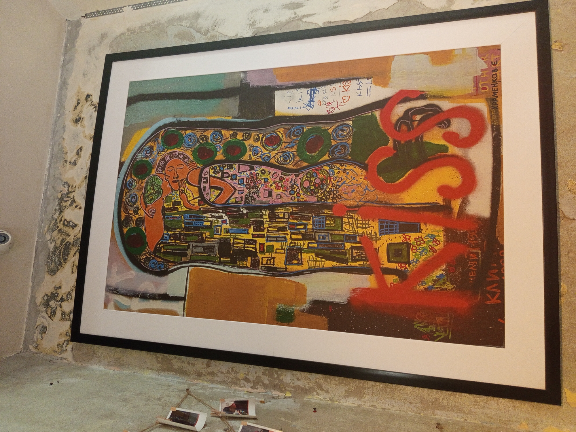 Framed abstract painting documented against partially painted indoor wall