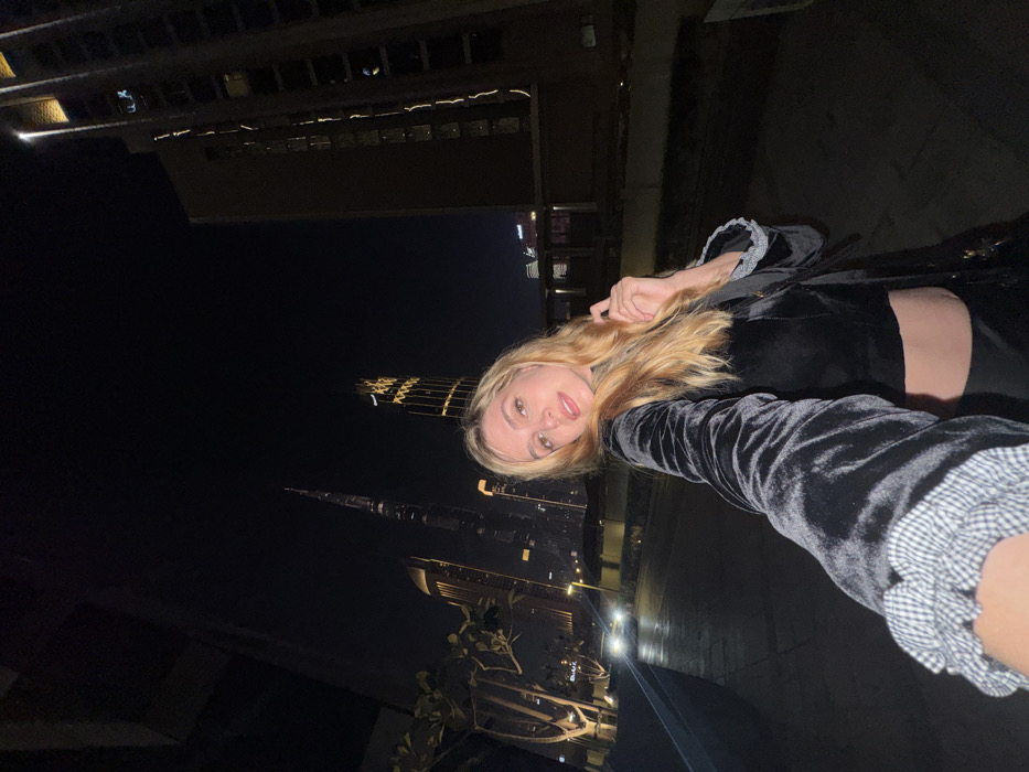 Woman photographs Dubai skyline selfies near Burj Khalifa at night