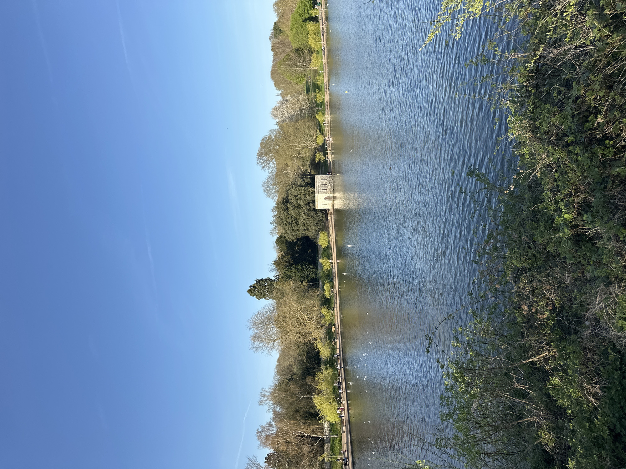 Pedestrians stroll lakeside pathway in Maidstone's Mote Park