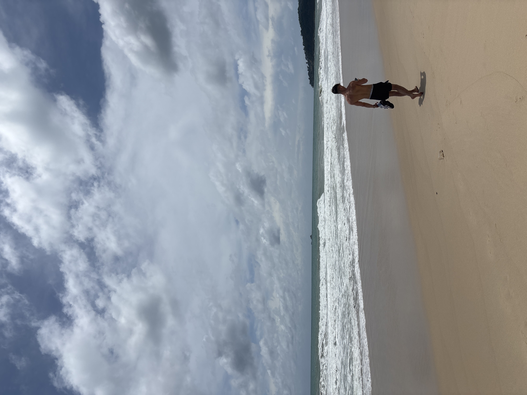 Man walks barefoot on Bang Tao beach, Thailand