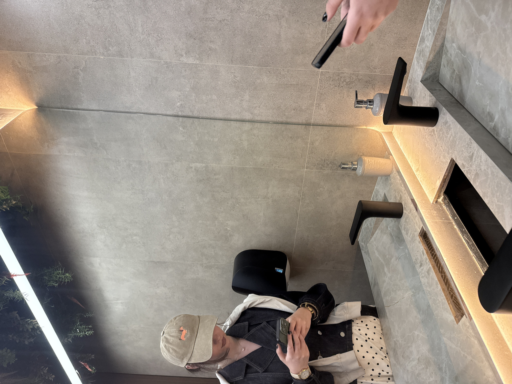 Person documented using phone in decorated Yerevan restaurant restroom