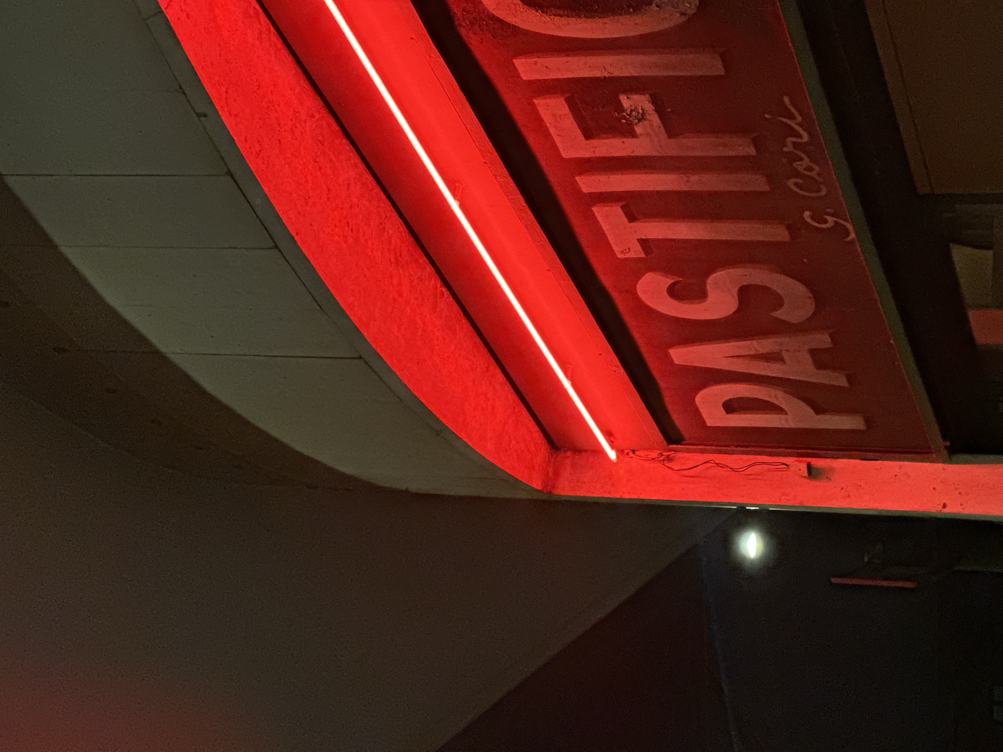 Illuminated red neon sign documented in Milan evening