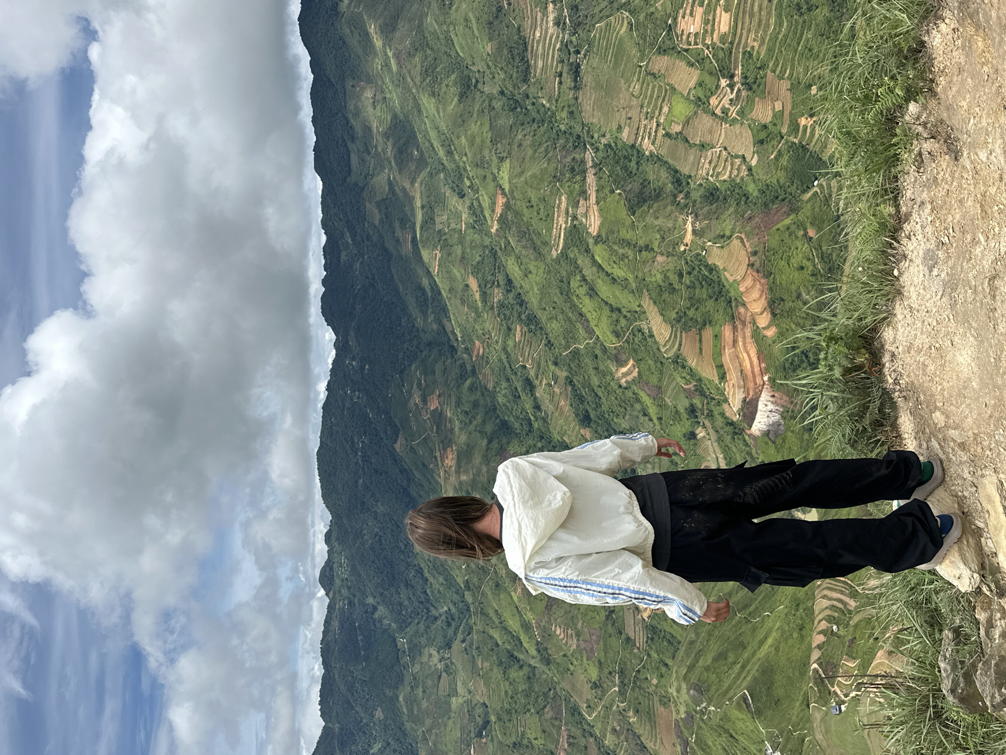 Person in striped jacket views terraced landscape at Ta Xua