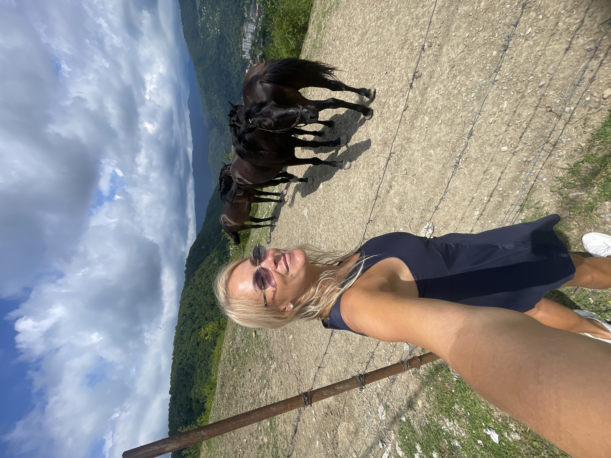 Dark horses on a Sochi hillside trail, valley views behind
