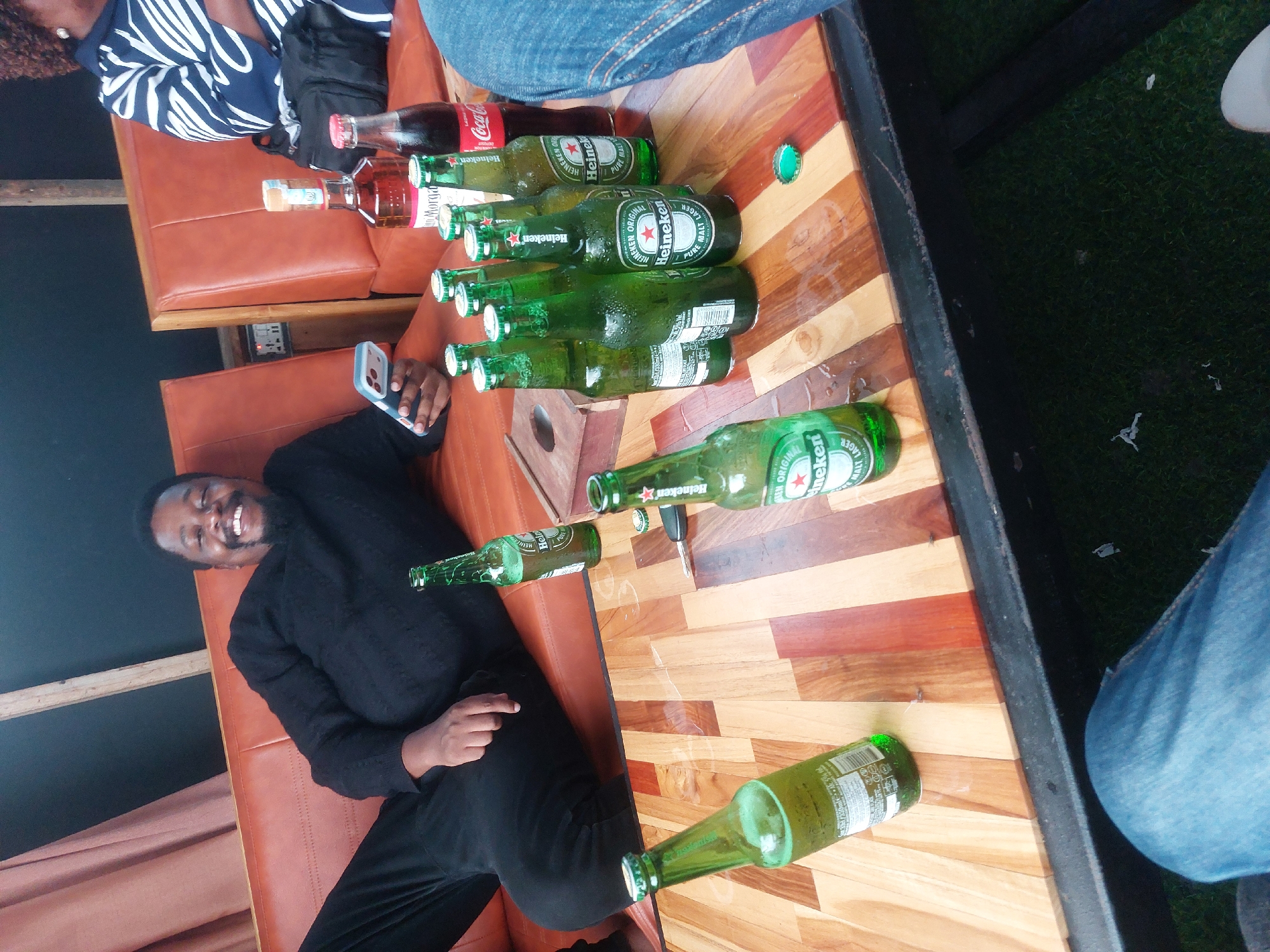 Man relaxes with phone at outdoor bar in Dar es Salaam