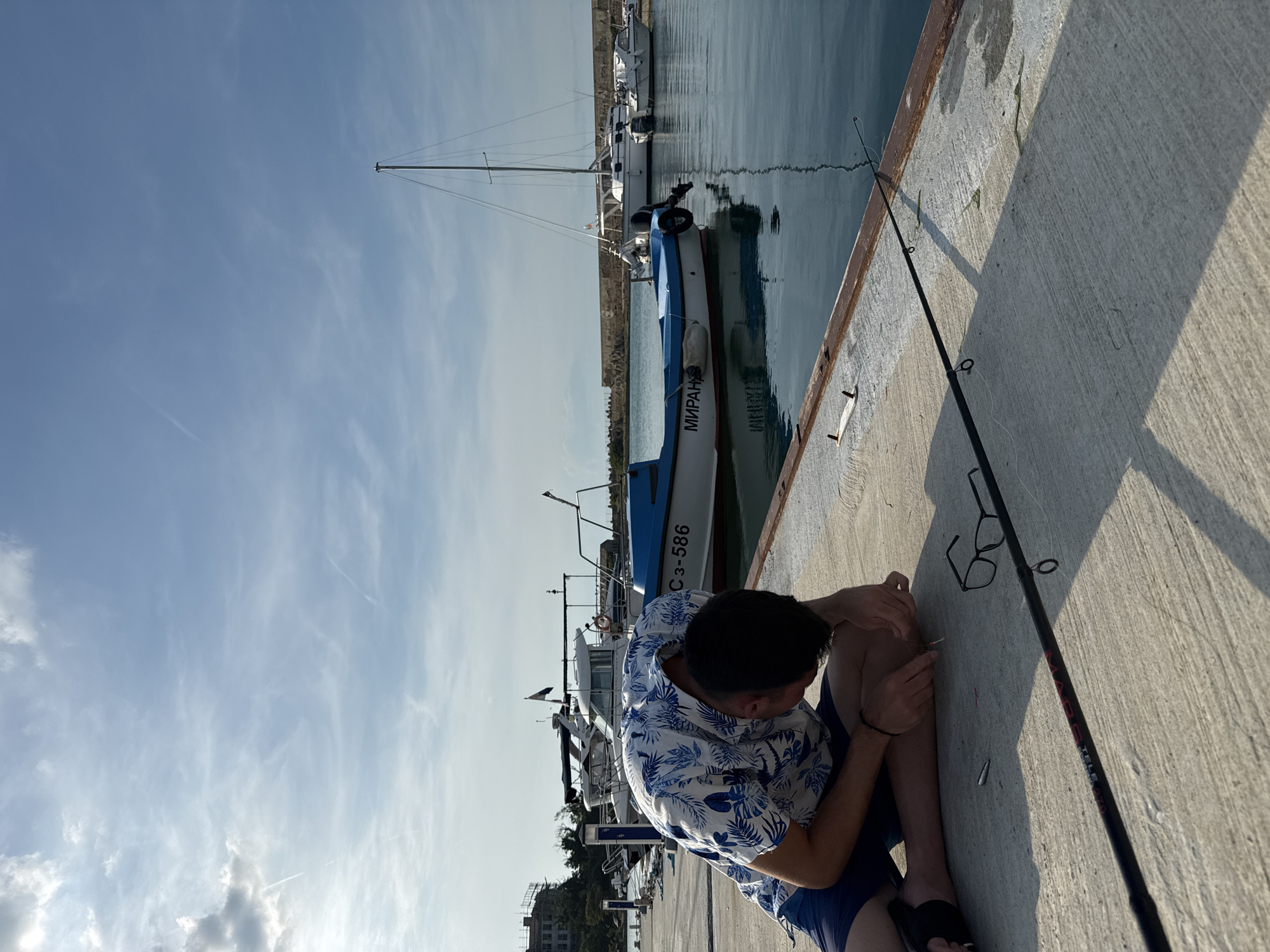 Young man fishing, kitten playing captured in Sozopol marina