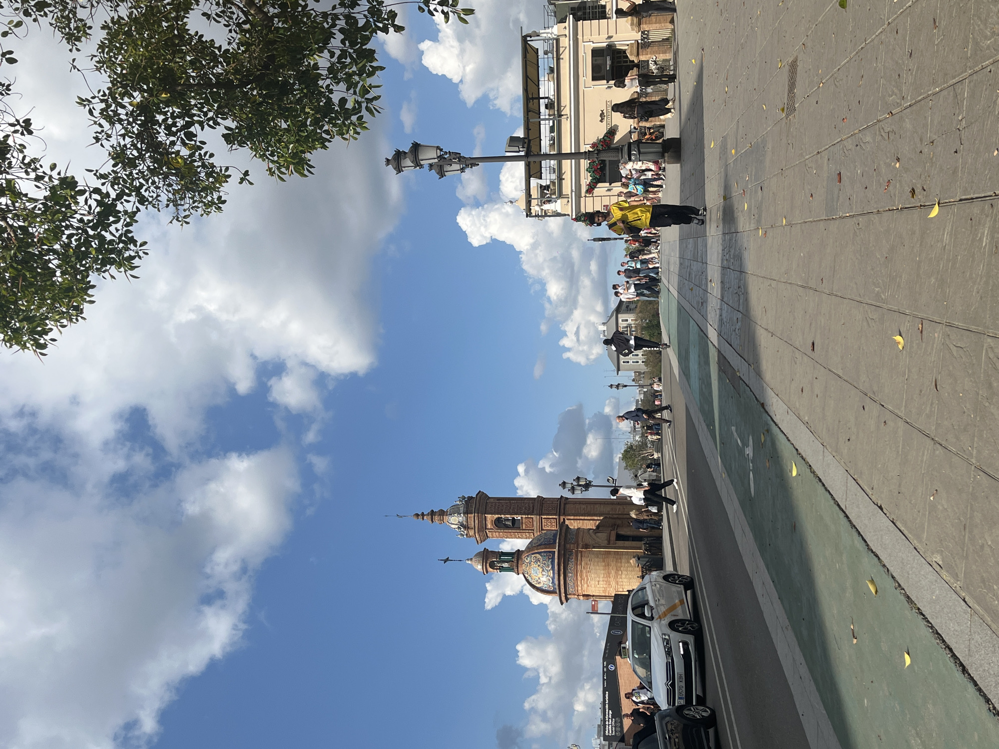 Visitor explores Plaza de España in Seville wearing fish pendant