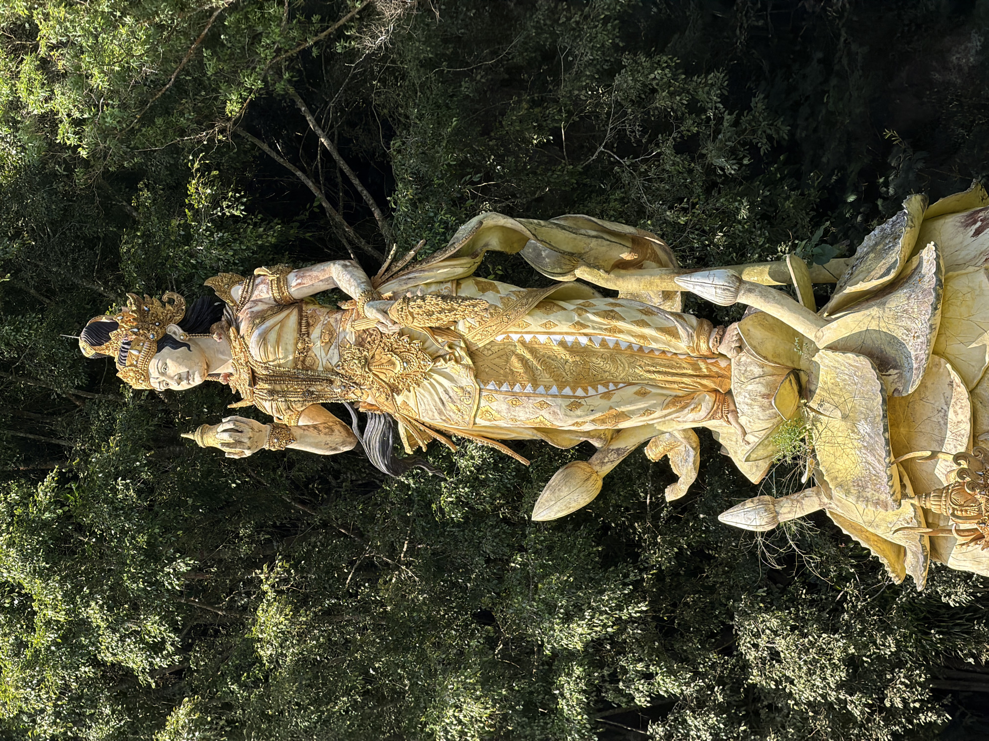 Golden statues rise from a green lake at Kintamani temple complex