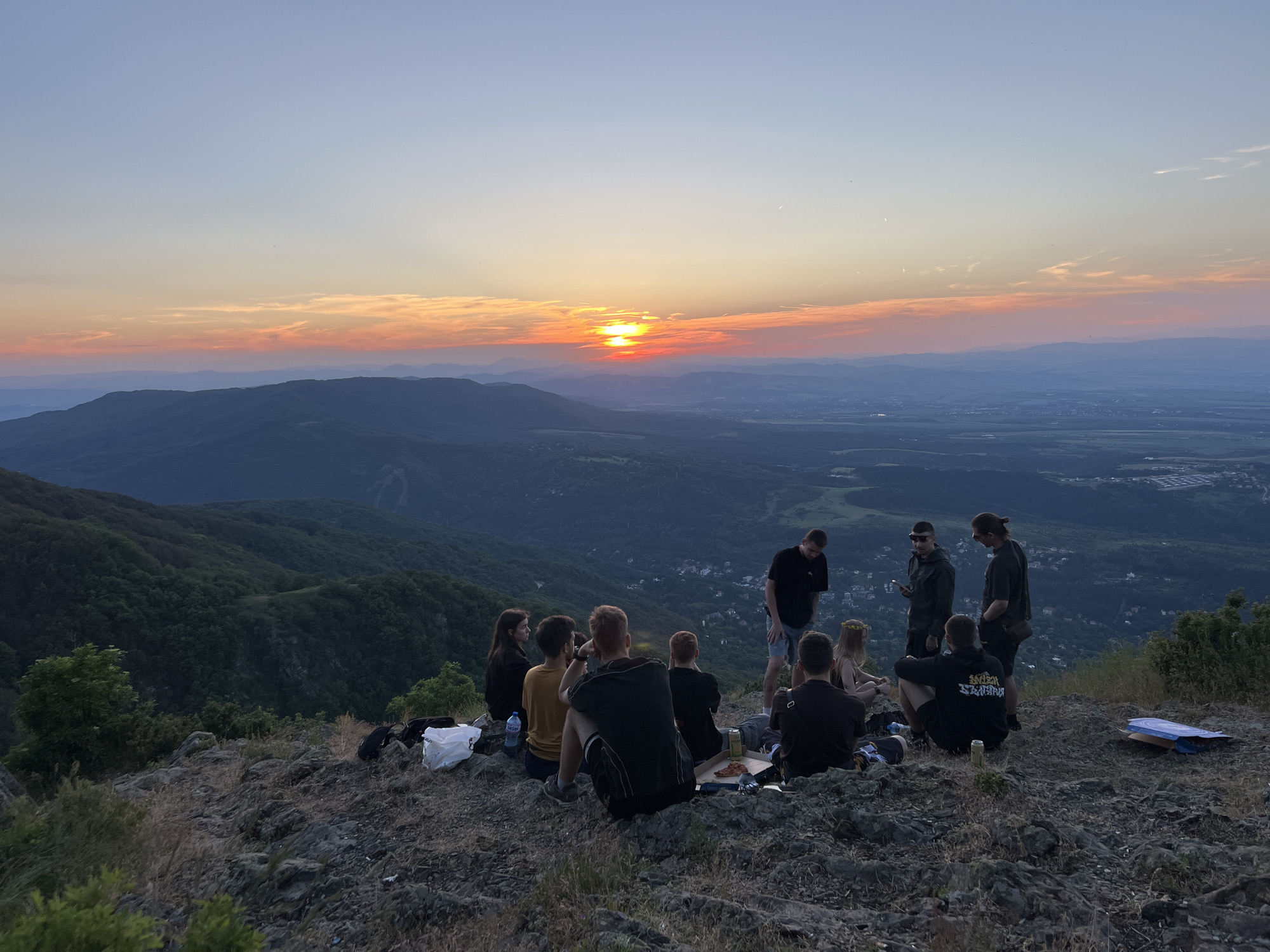 Groups gather on hilltops to witness sunset over valleys