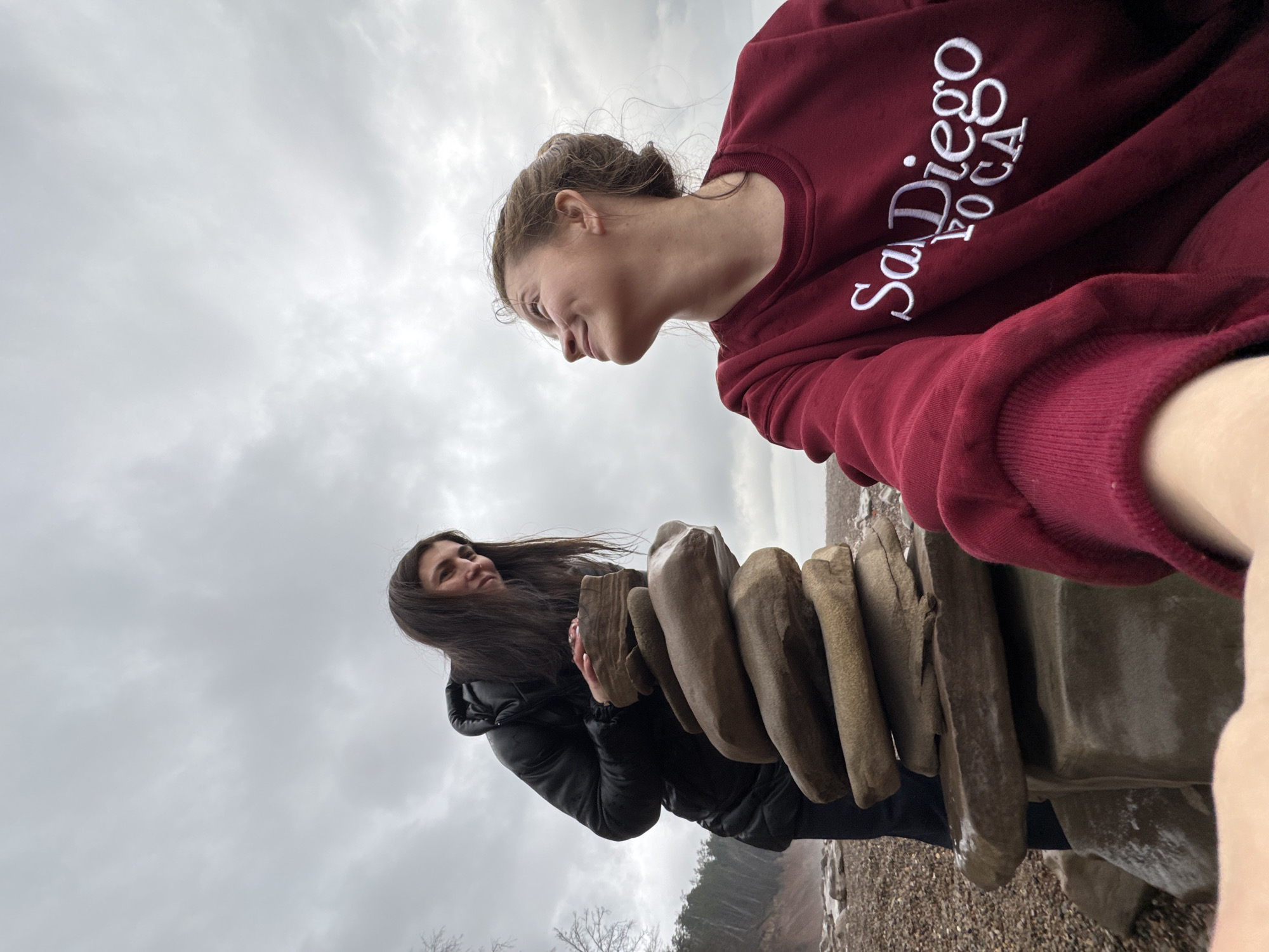 Two women gather near stacked rocks by waterway in Russia