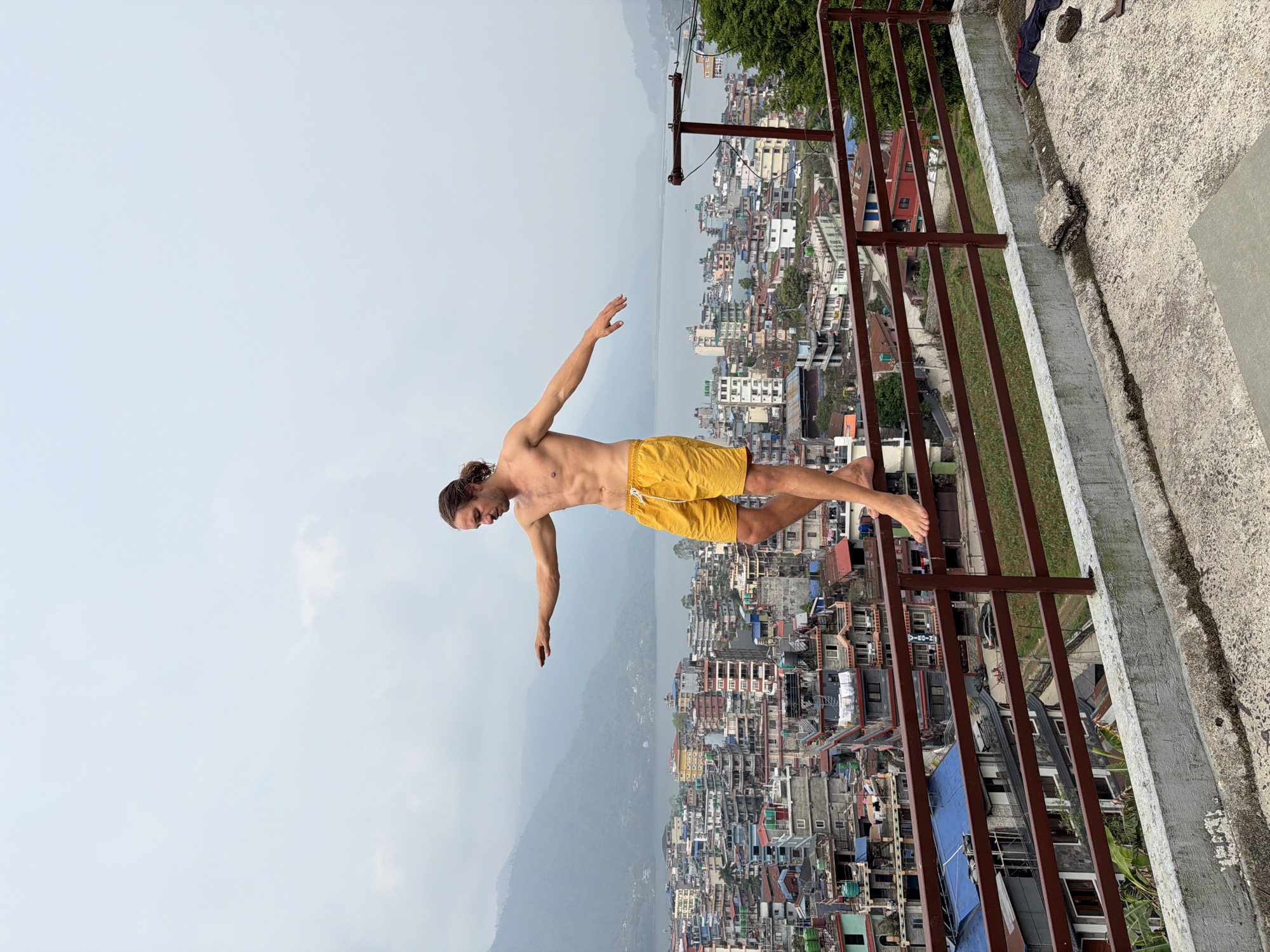 Man balances on rooftop railing overlooking Pokhara Nepal