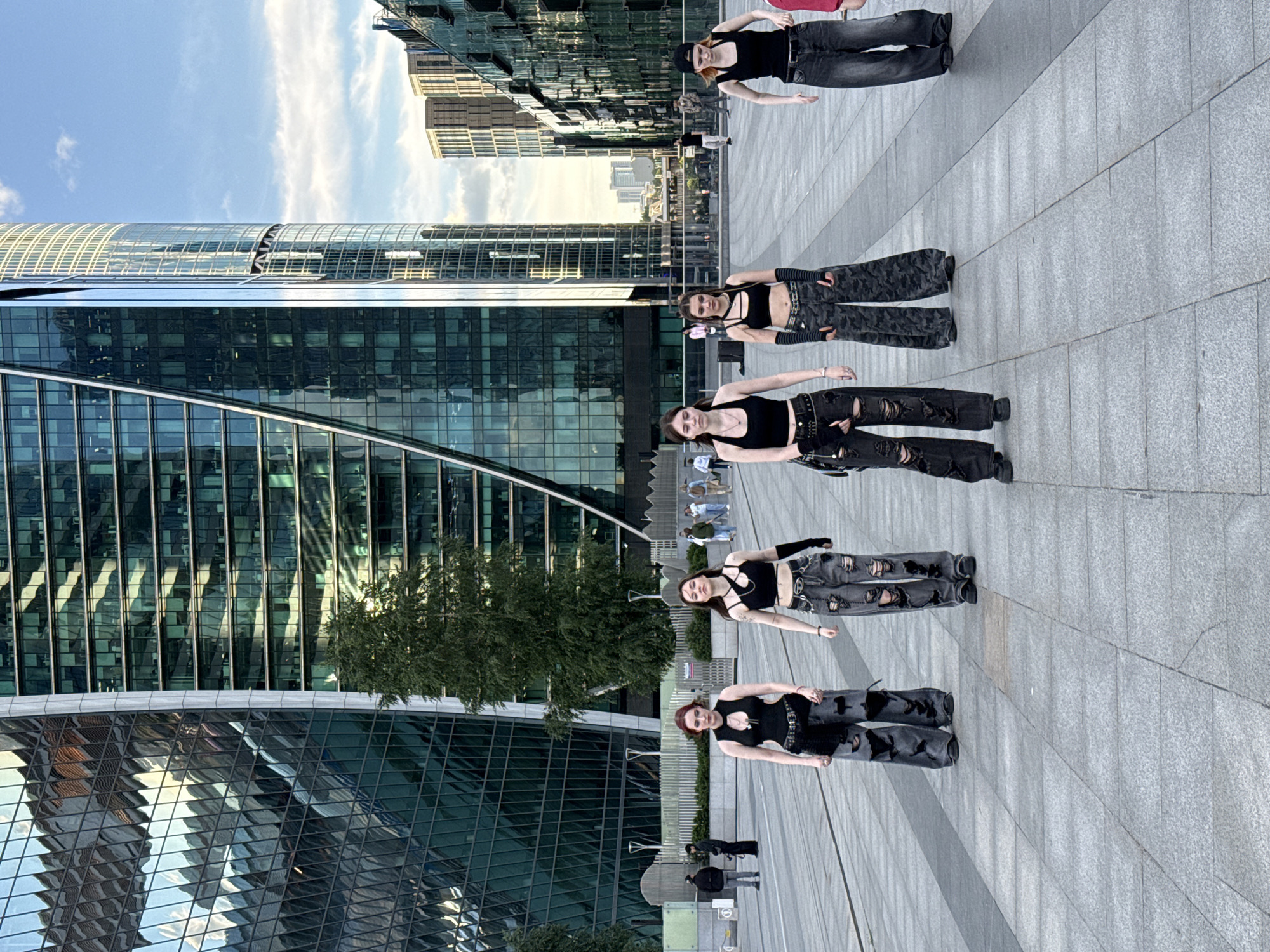 Streetwear crew dancing in a downtown plaza among skyscrapers