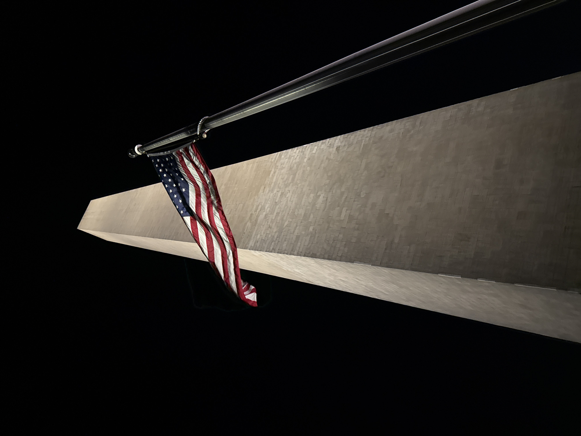 Washington Monument photographed illuminated at night with American flag