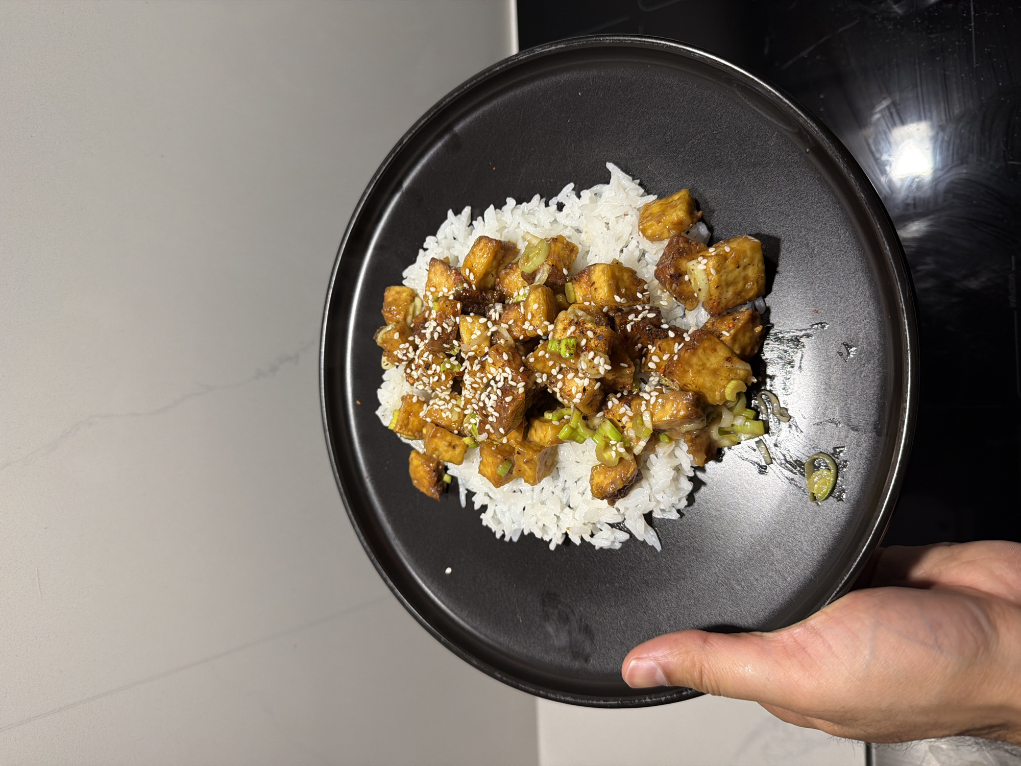 Person serves rice and glazed tofu dish in London