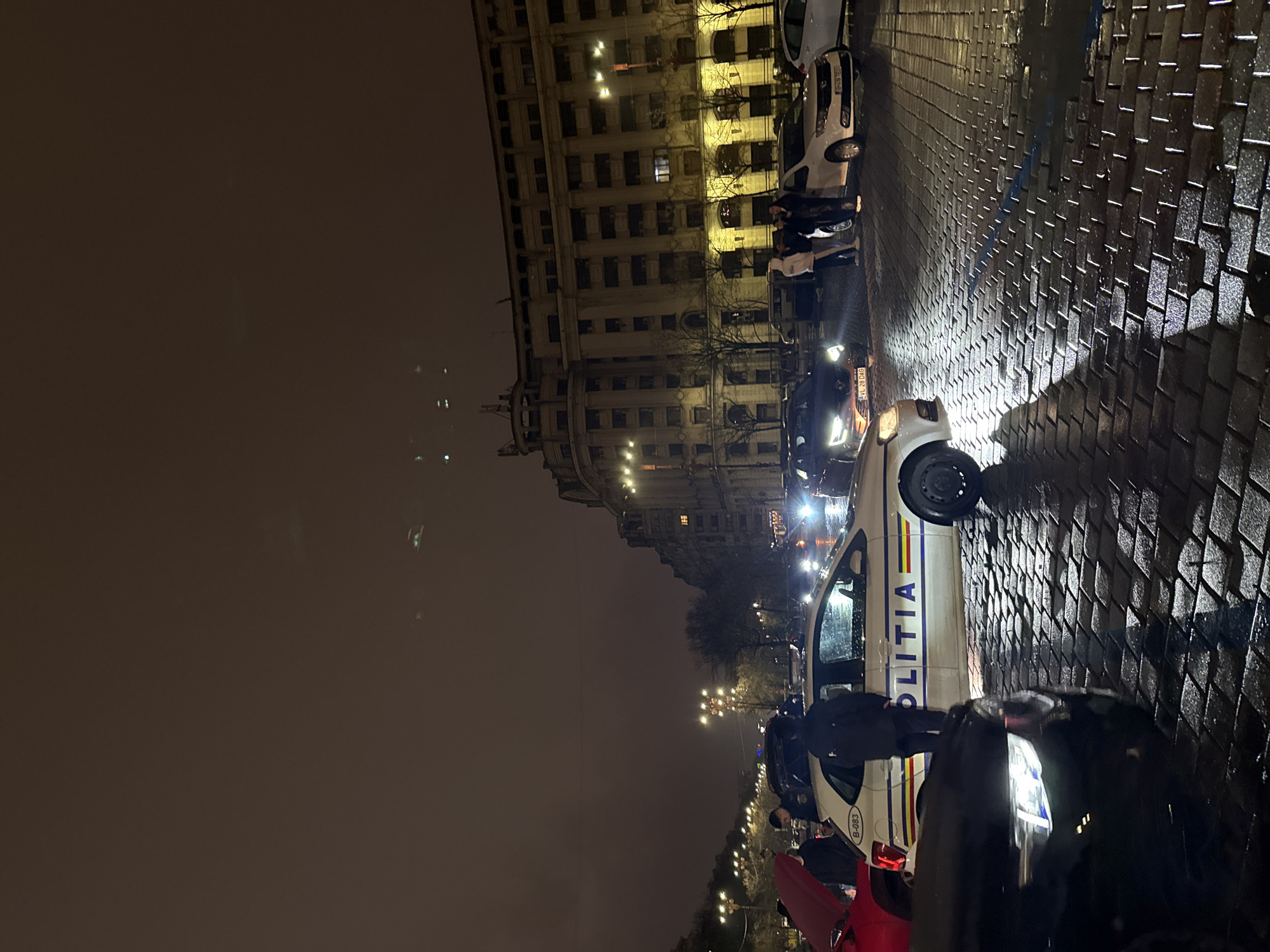 Police patrol wet streets near Palace of Parliament, Bucharest