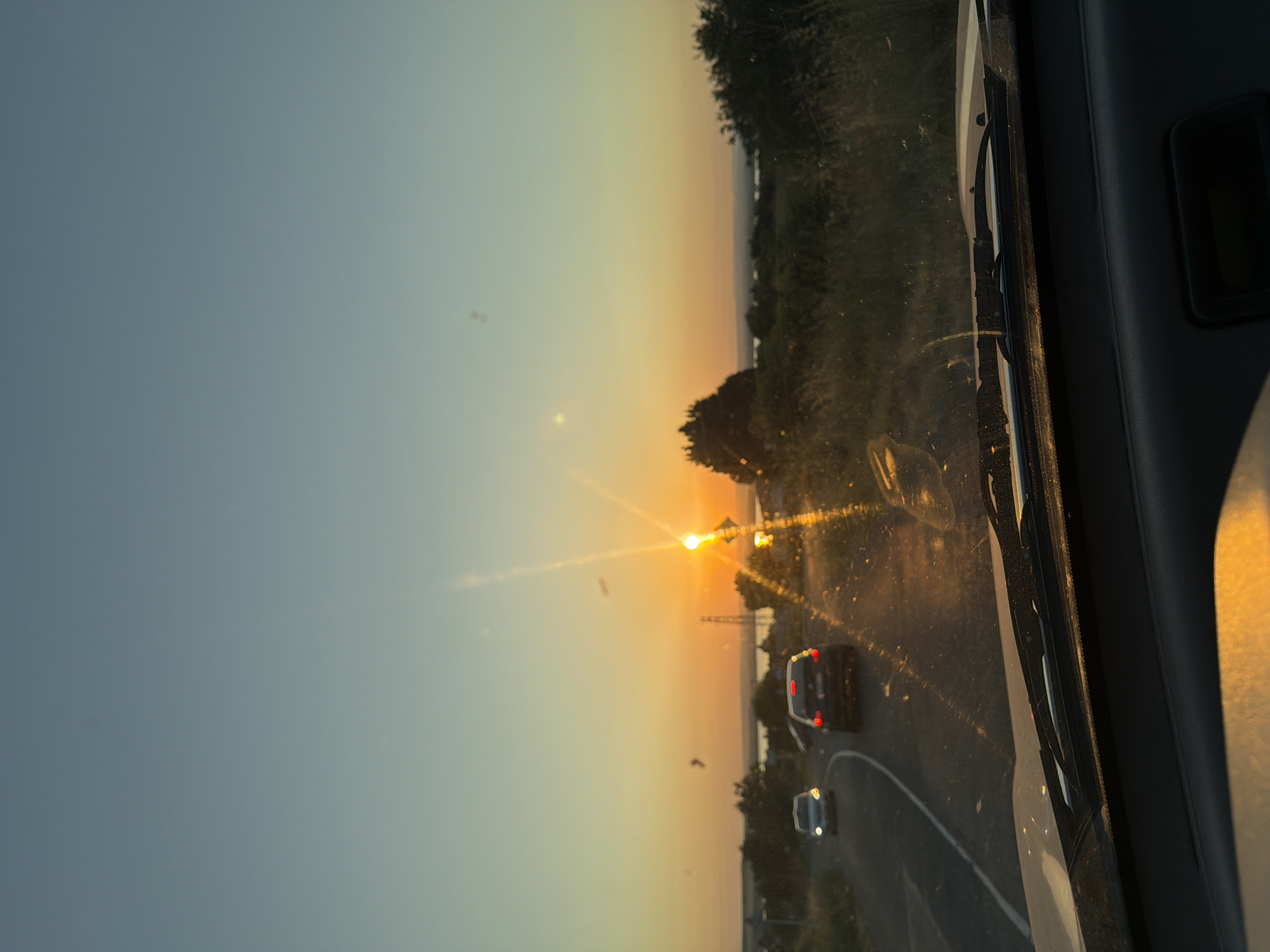 Golden sunset through a windshield, sun low on the horizon