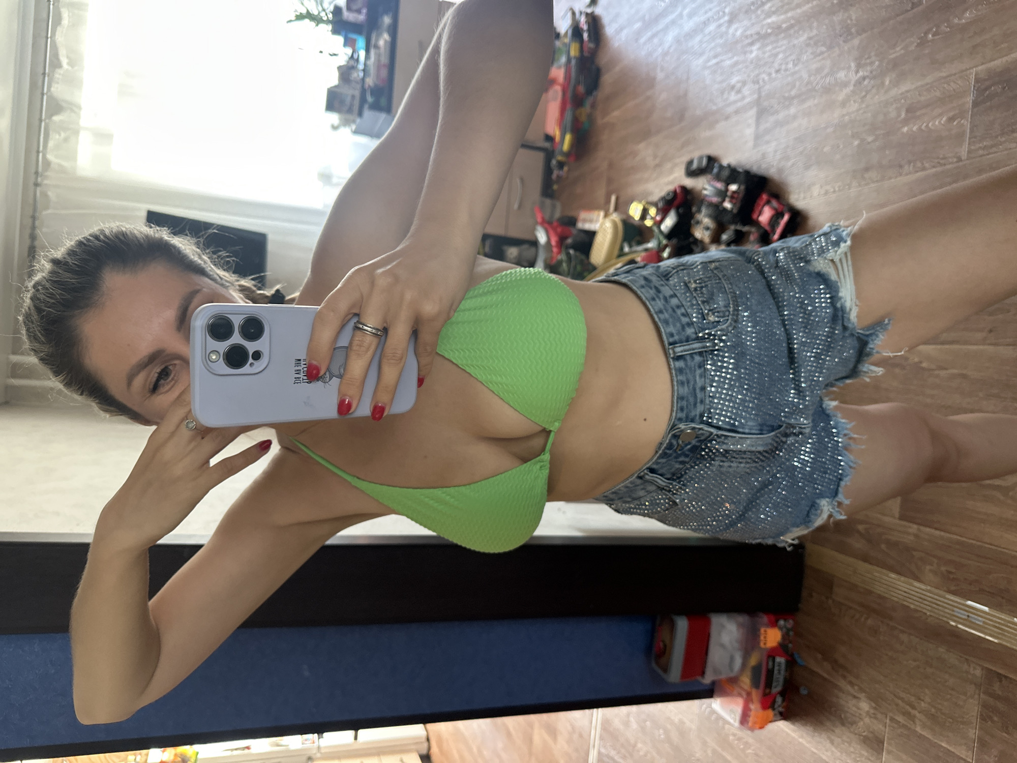 Mirror selfie in Novoaltaysk: neon green top, rhinestone denim shorts