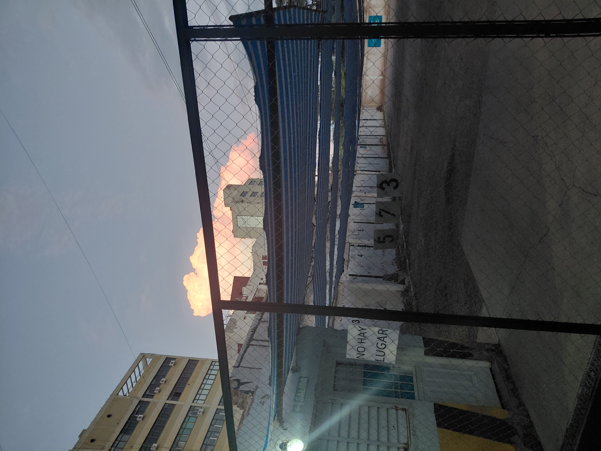 Chain-link fence view of multistory buildings in Mendoza