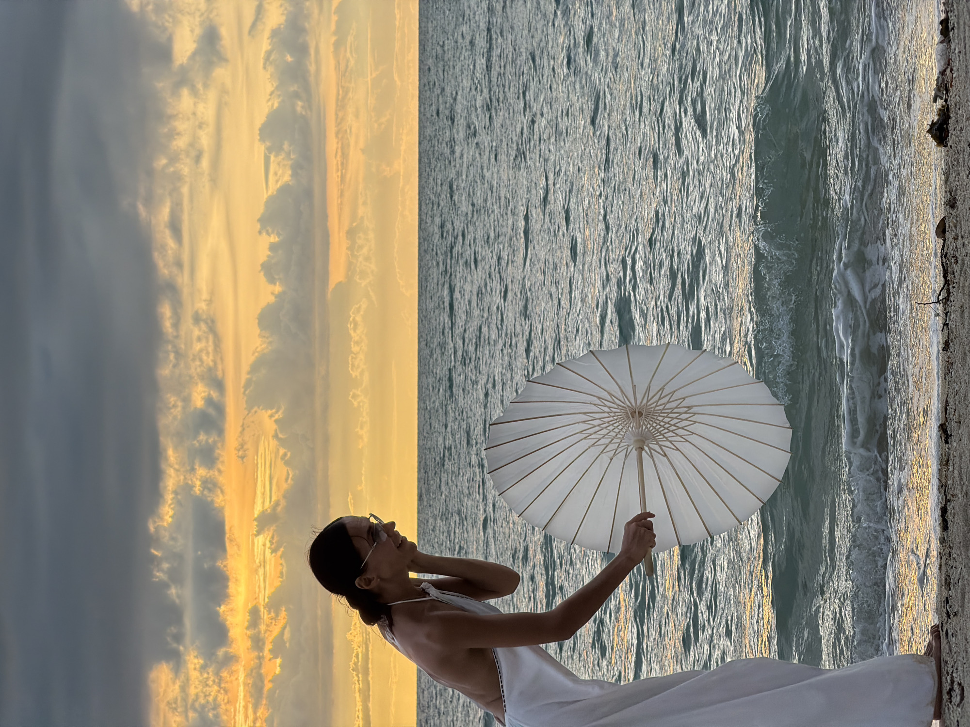 White dress, parasol, and a dramatic sunset at Baan Plai Laem