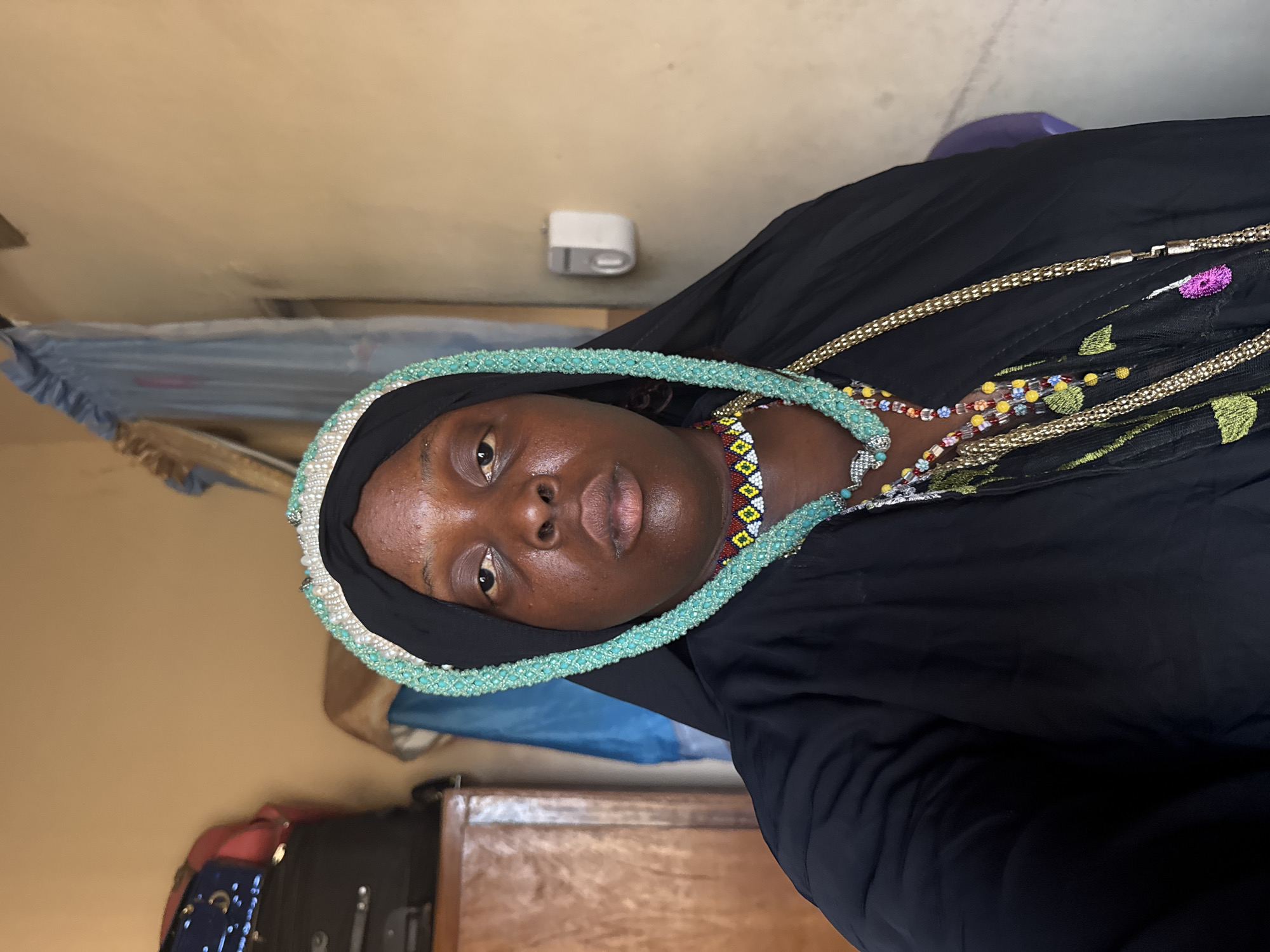Woman in traditional dress displays jewelry in Madangala
