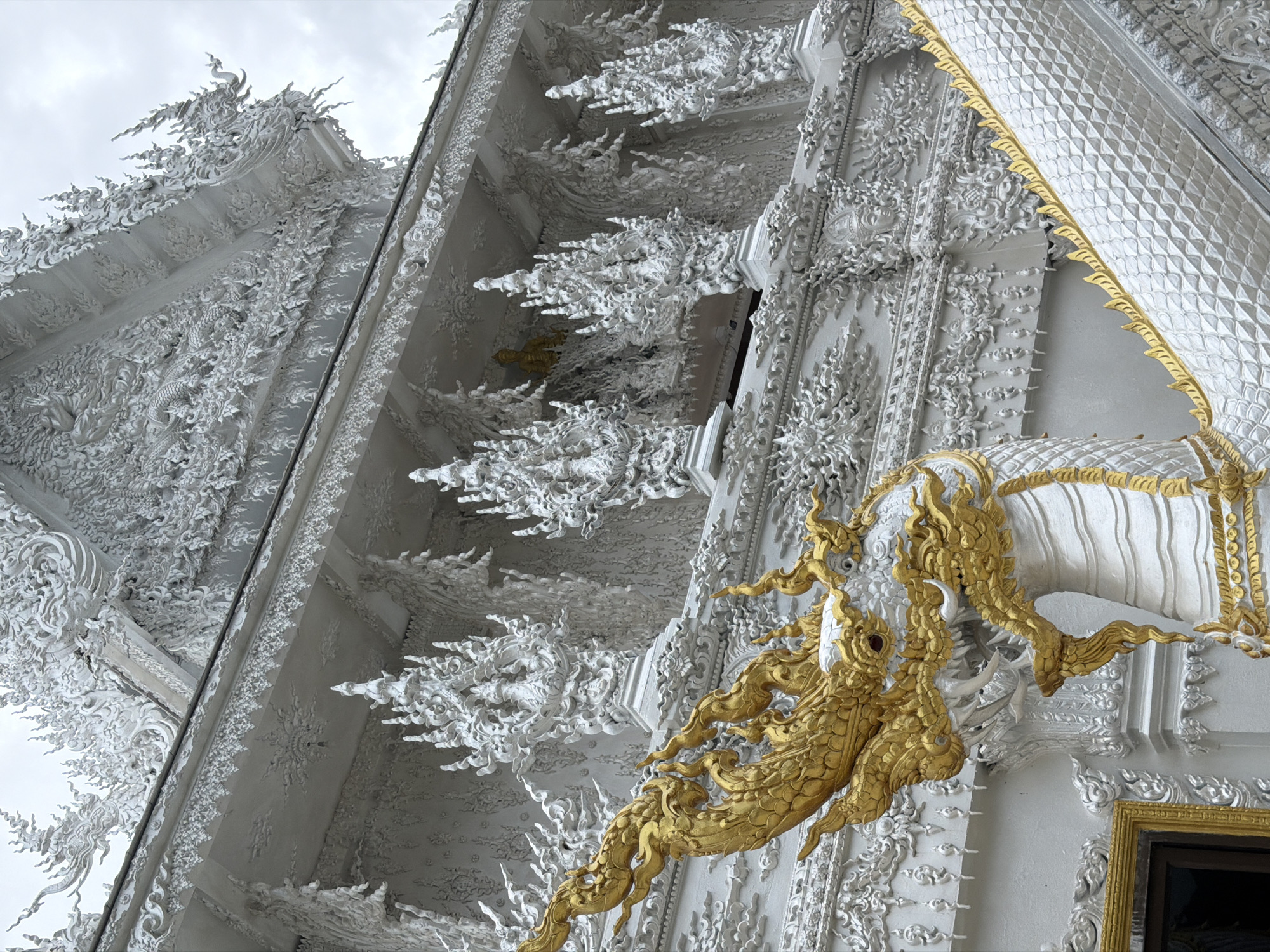Visitor documents Thailand's White Temple from multiple angles during rainstorm