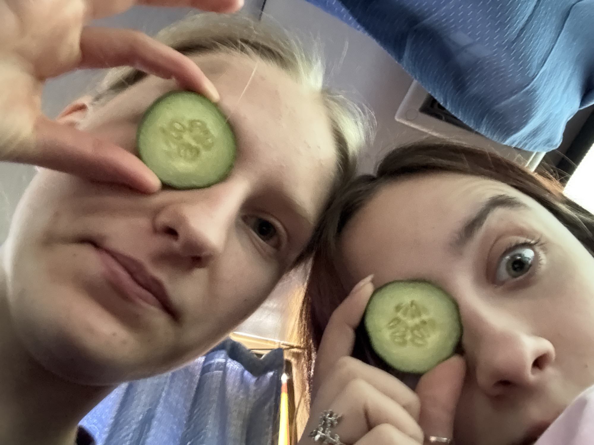 Two people pose with cucumber slices over eyes in Russia