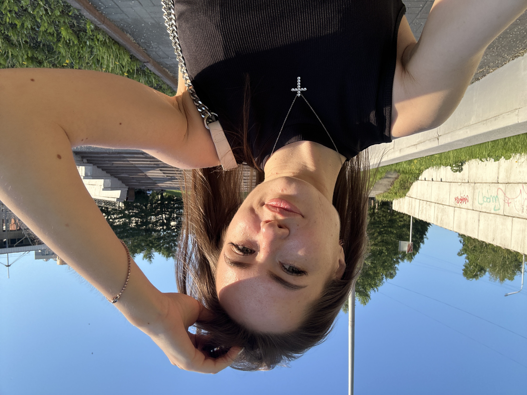 Woman takes selfies near modern building during sunny afternoon