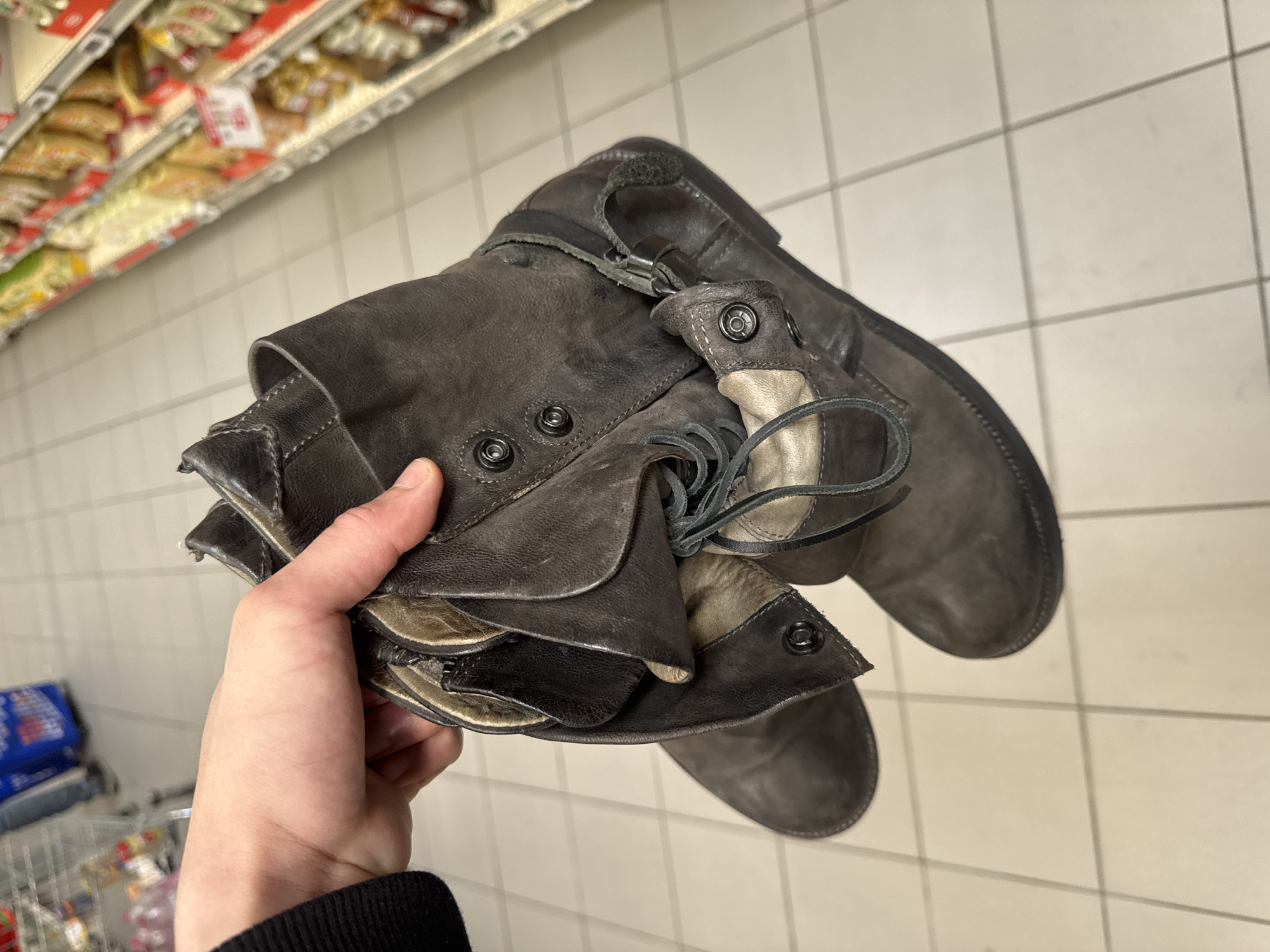 Person holds worn leather boots in Les Ulis store