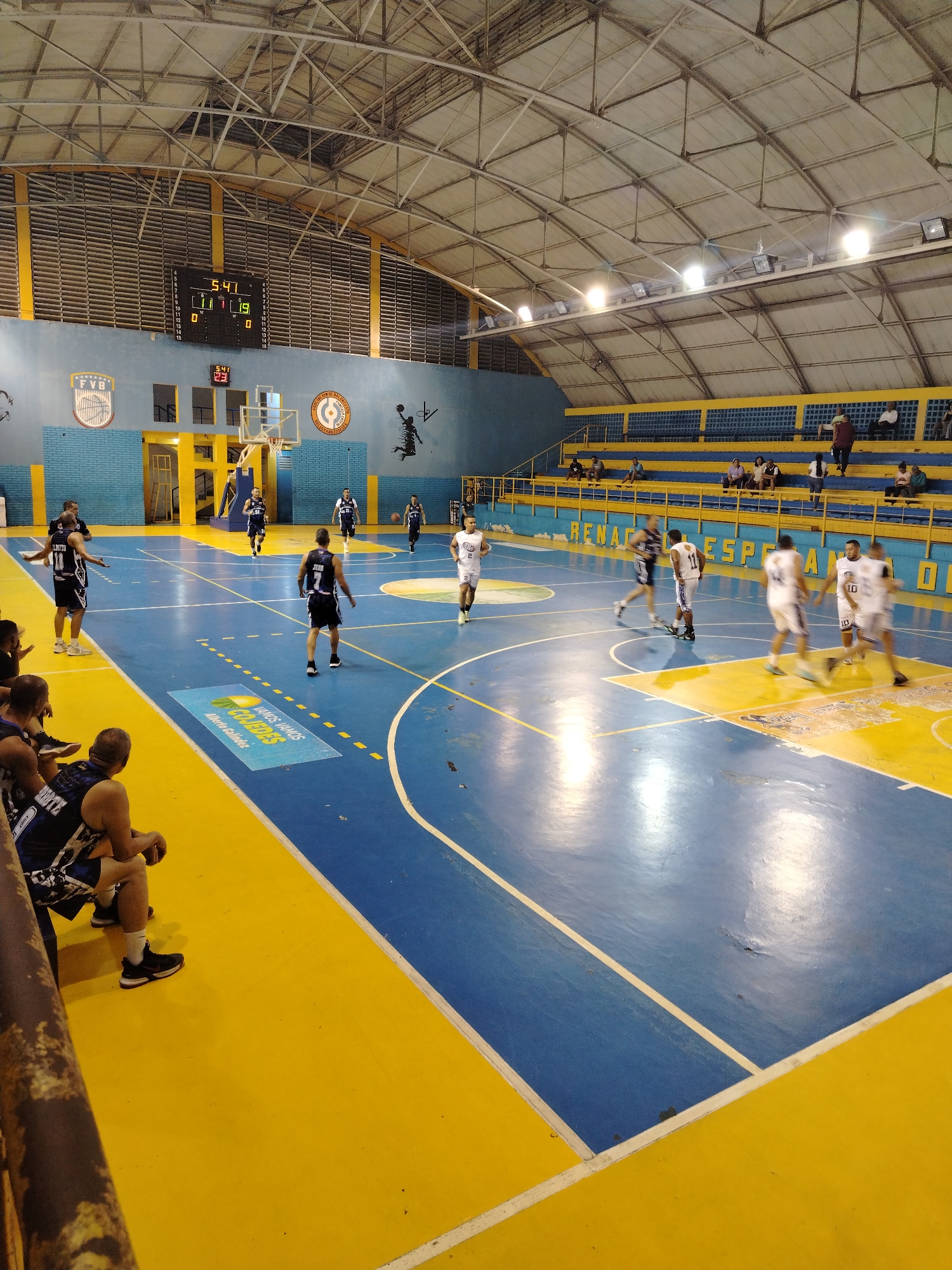 Basketball game observed in Tinaquillo gymnasium during evening hours