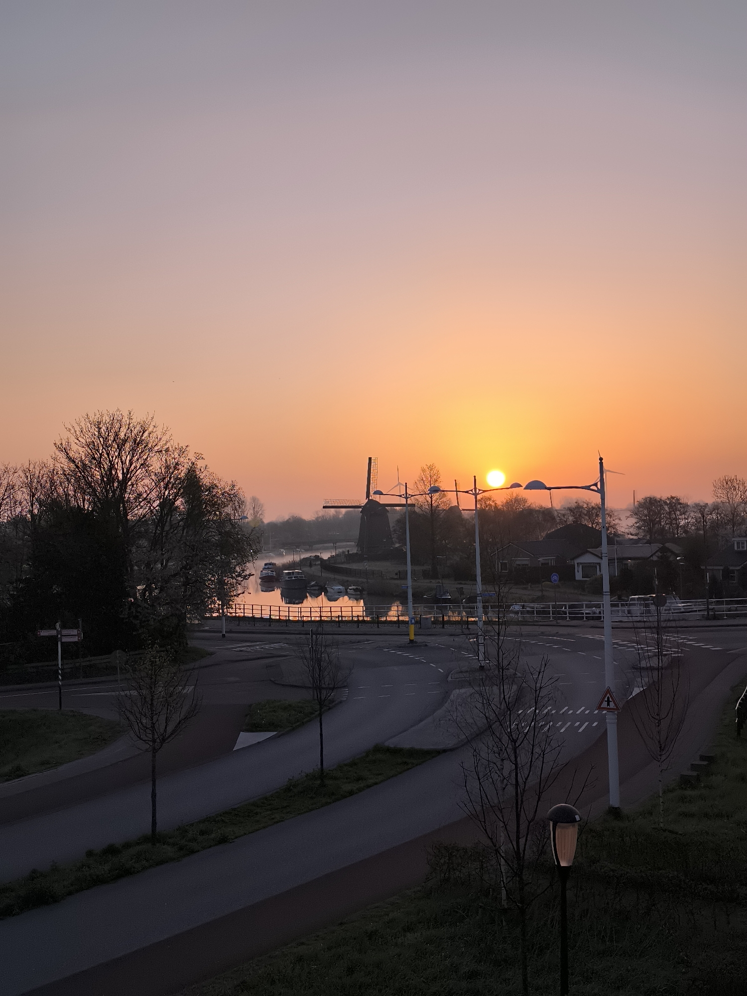 Sunrise illuminates windmill and canal in Alkmaar streetscape