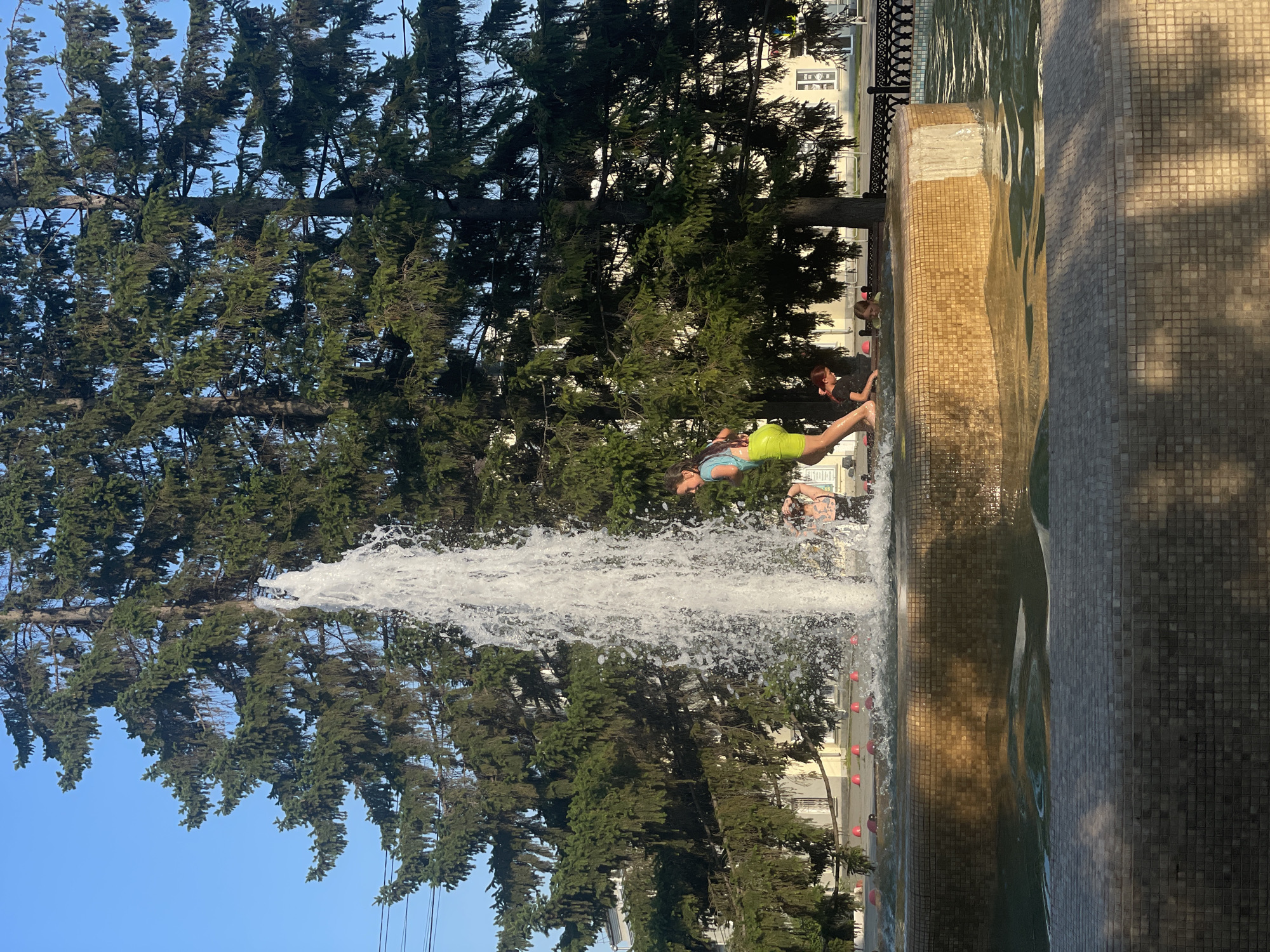 Kids cool off in a city park fountain on a summer day