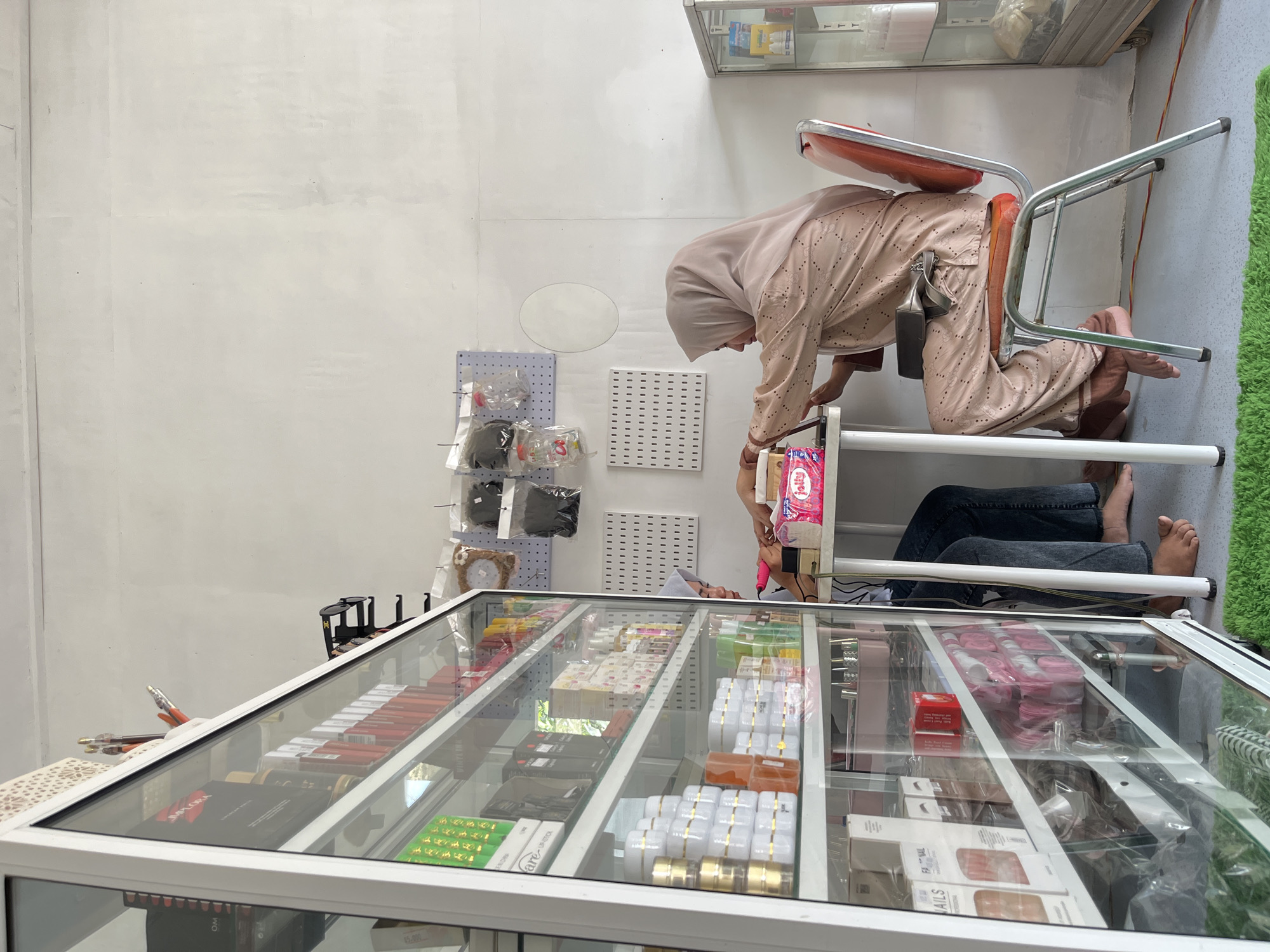 Woman examines display case in Lhokseumawe shop