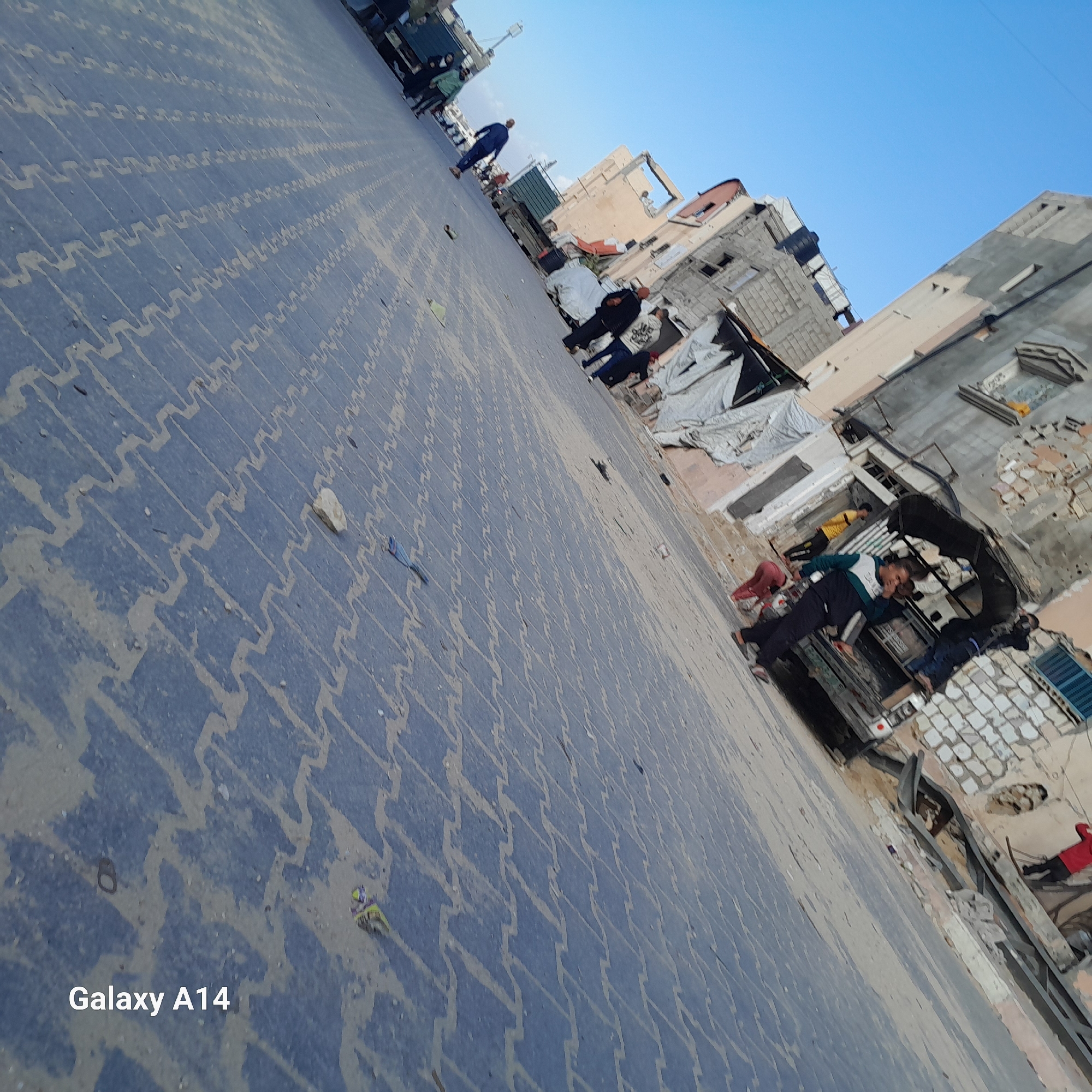 Pedestrians navigate paved streets in Khan Yunis under clear skies